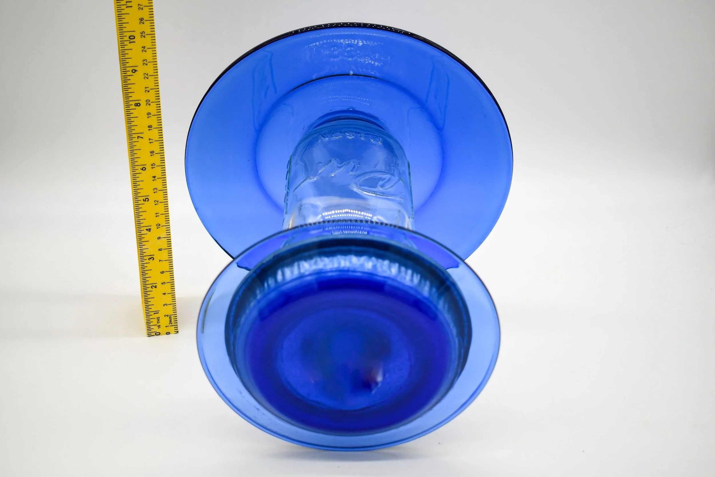 Top view of royal blue glass bird feeder showing large upper weather shield and lower glass plate