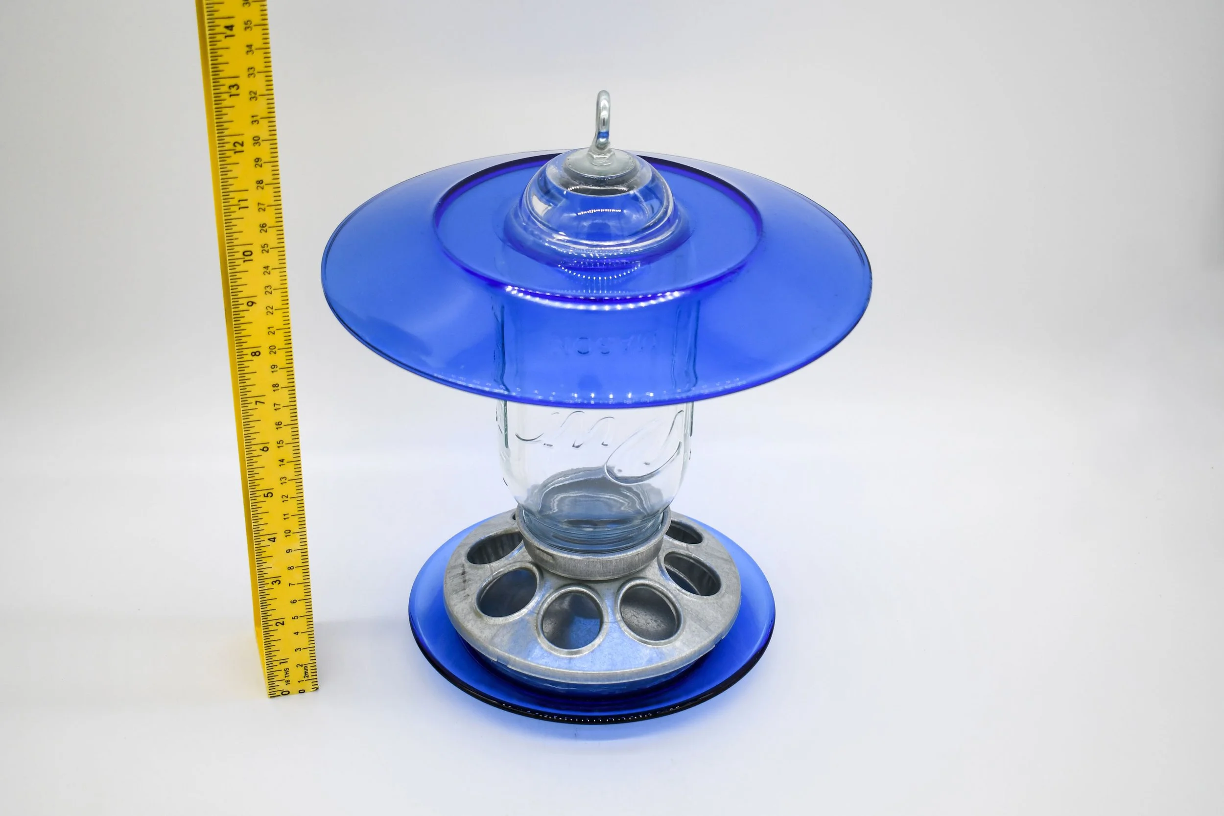 Royal blue glass hanging bird feeder with ruler showing feeder height and wide glass weather shield