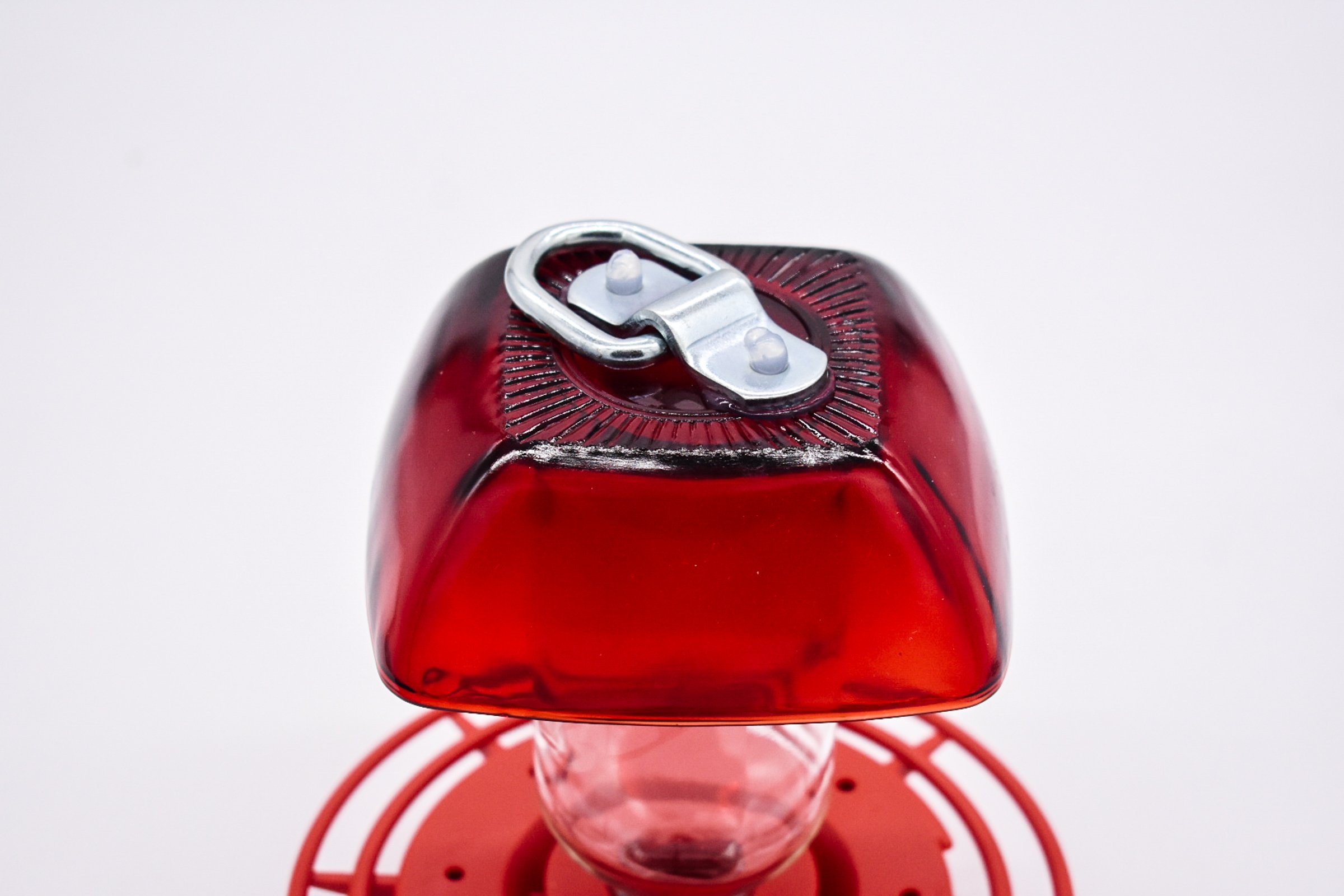 Tilted Side view of the Anchor Hocking Ruby Red Berry Bowl glass with 8 oz reservoir and red Best 1 plastic hummingbird feeder on a white background.