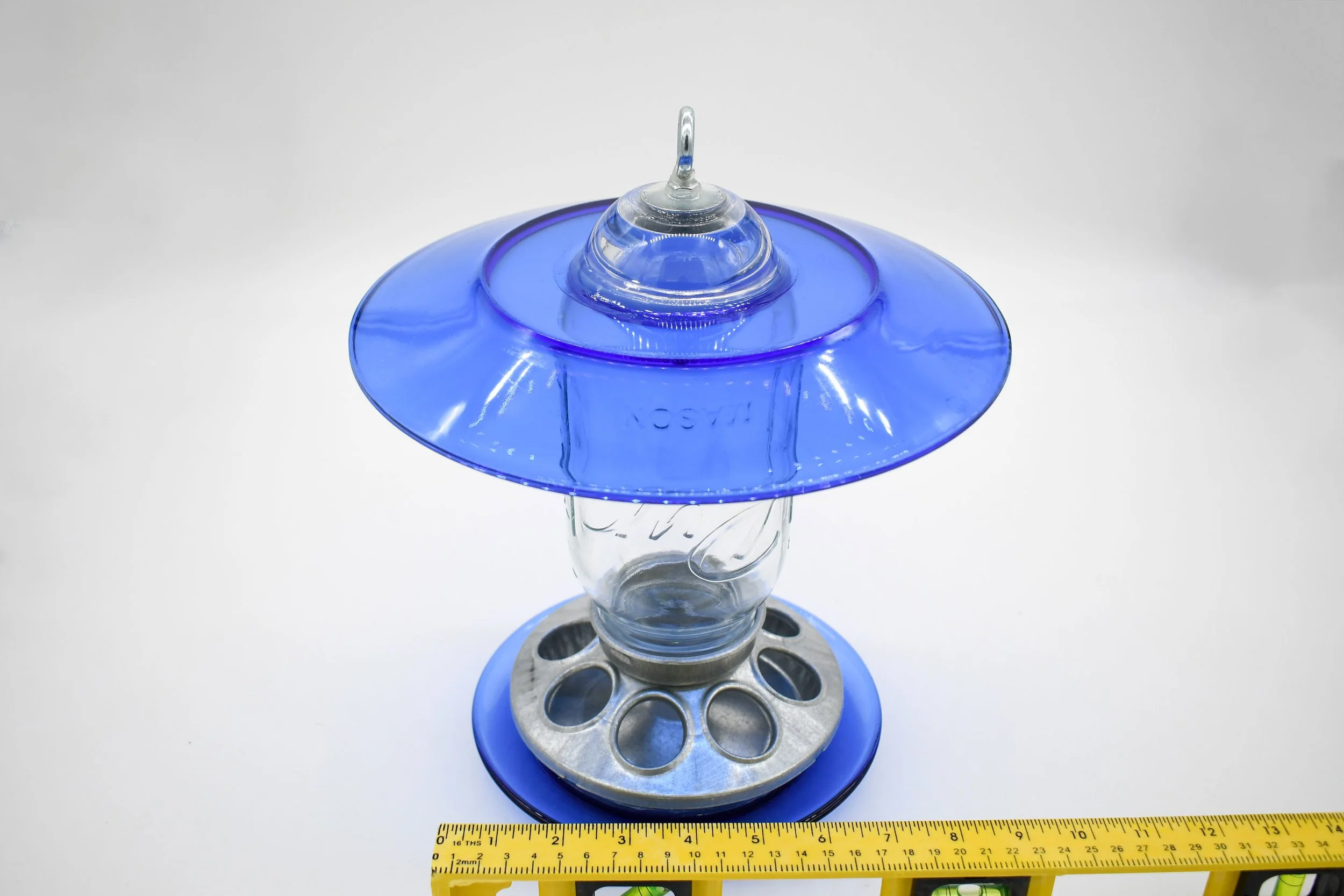 Angled view of royal blue glass bird feeder showing upper weather shield and feeding base dimensions