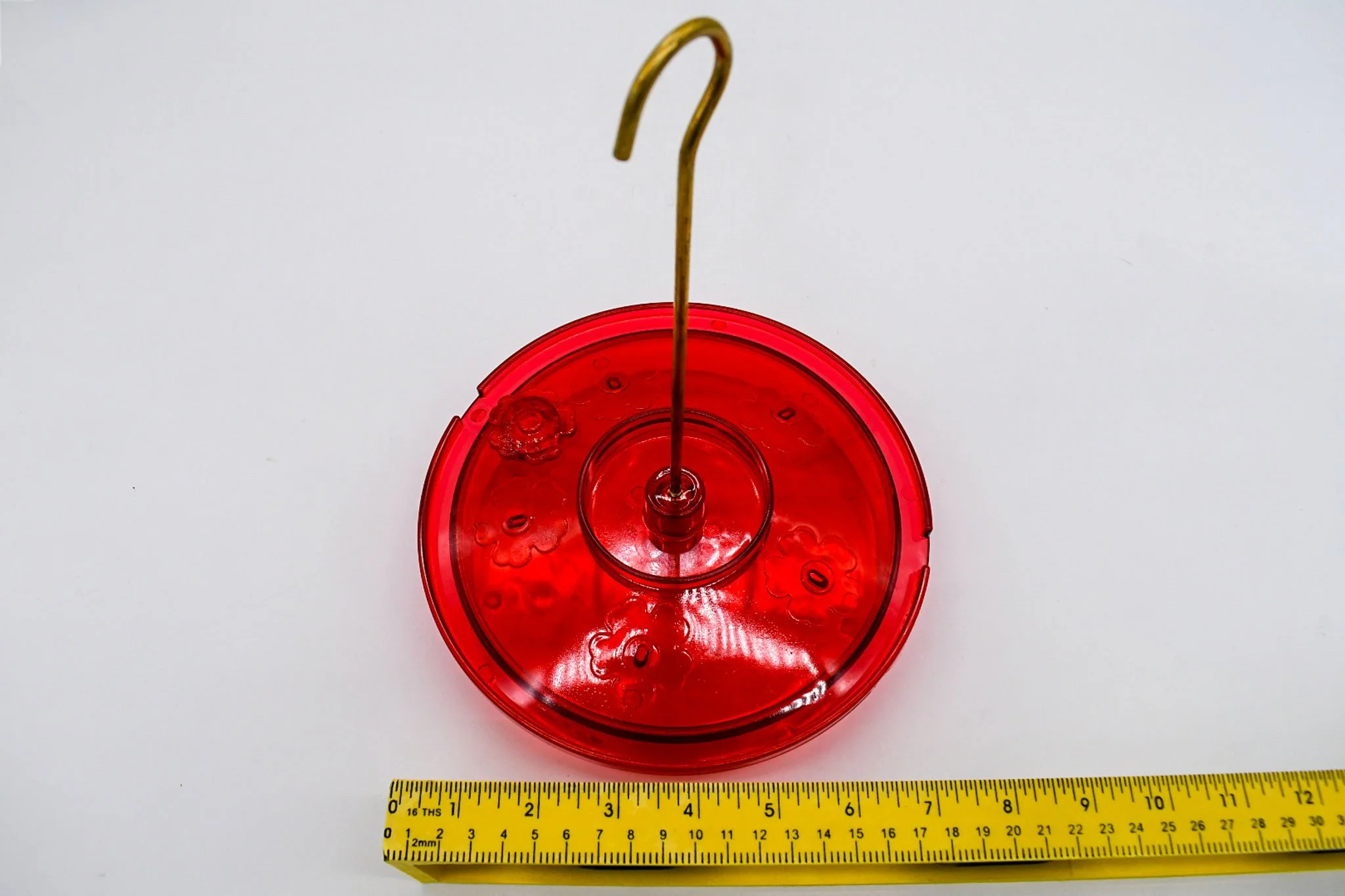Front view of the red Hummingbird Haven feeder with a ruler showing its approximate width.