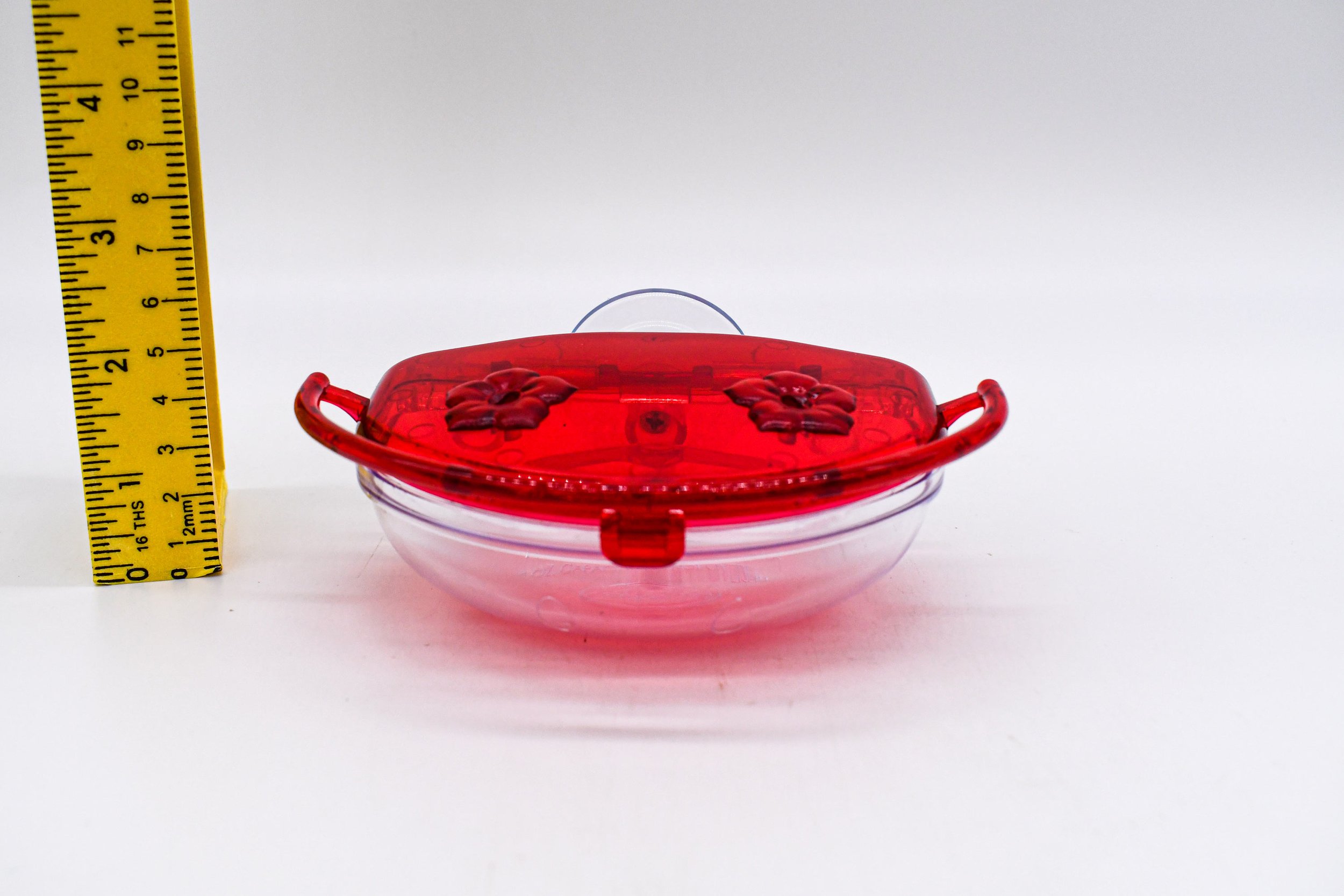 Low front view of the Aspects The Gem 4 oz Window Hummingbird Feeder showing the dual flower feeding ports, integrated perch, and clear nectar reservoir.