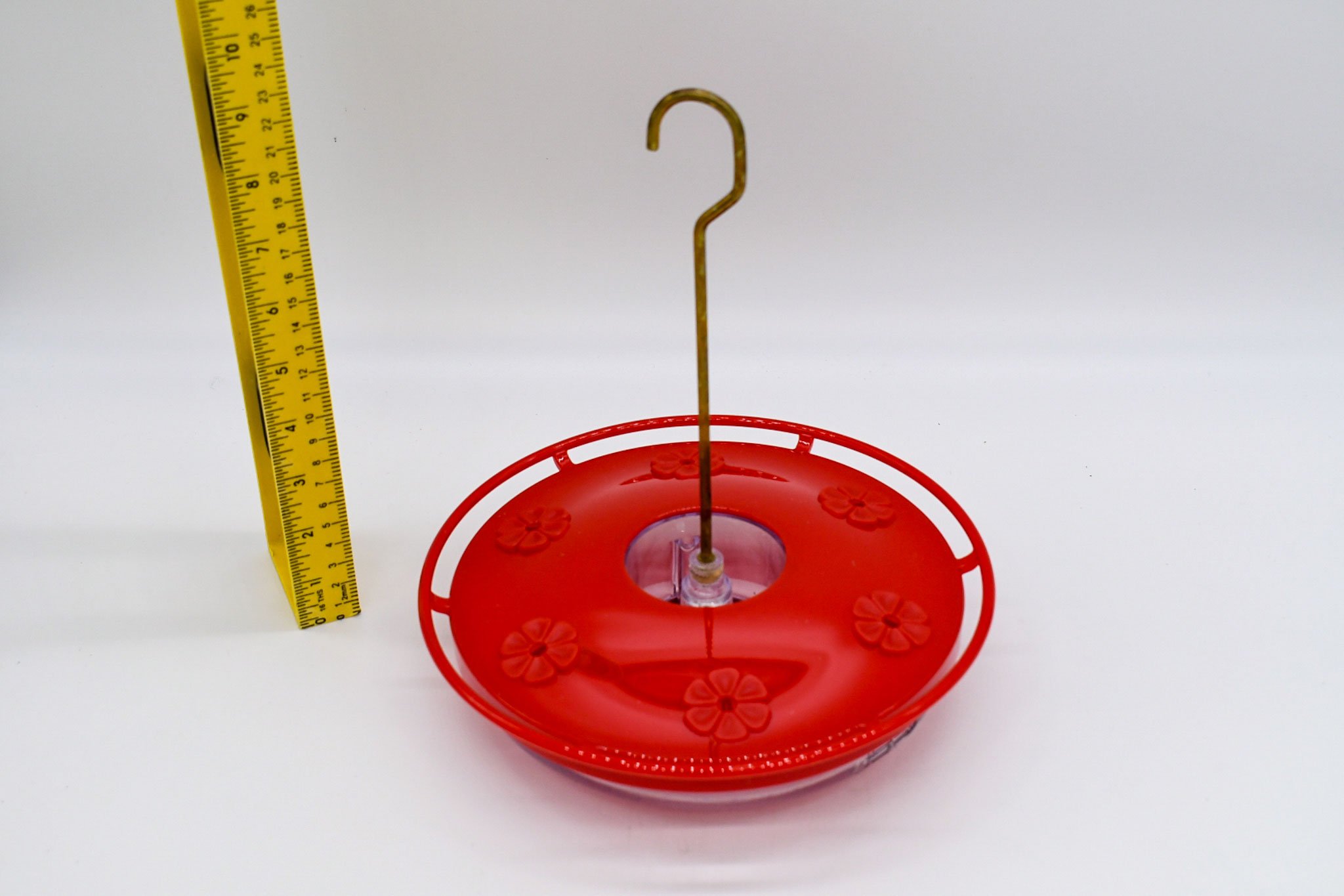 Angled side view of the red Aspects HighView Excel feeder with its brass hanging hook and measuring tape.