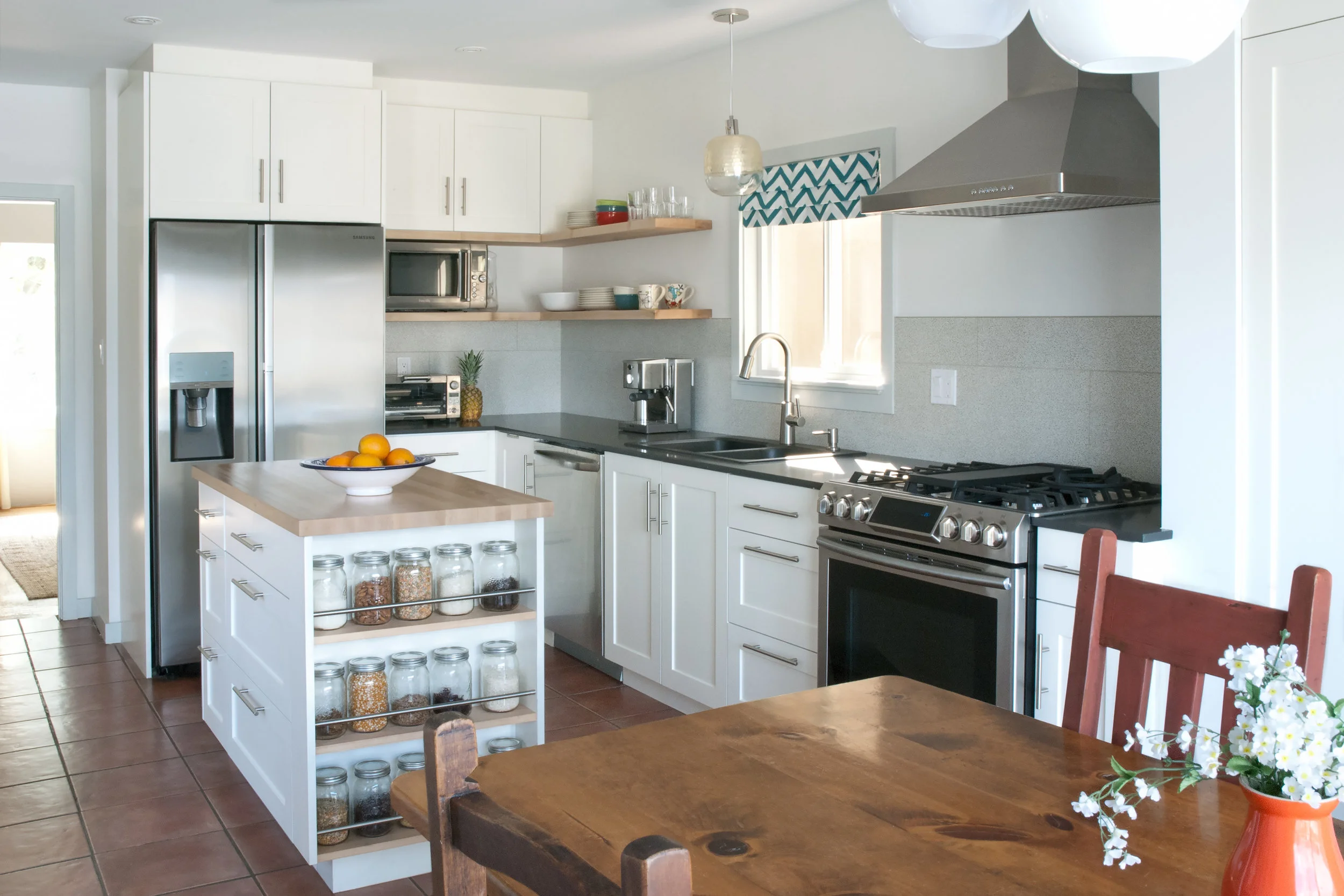 This project involved a complete kitchen rehab for a family who had just moved into this charming character house in East Vancouver. Due to budgetary constraints, we chose to save the existing terracotta tile in the room, but completely reconfigured the room's layout to create more storage and a family-friendly eating space. We also added a kitchen island, sized to fit the long, narrow room while providing ample working space. The open-ended storage on the island gives the kitchen a relaxed, casual feel. 
