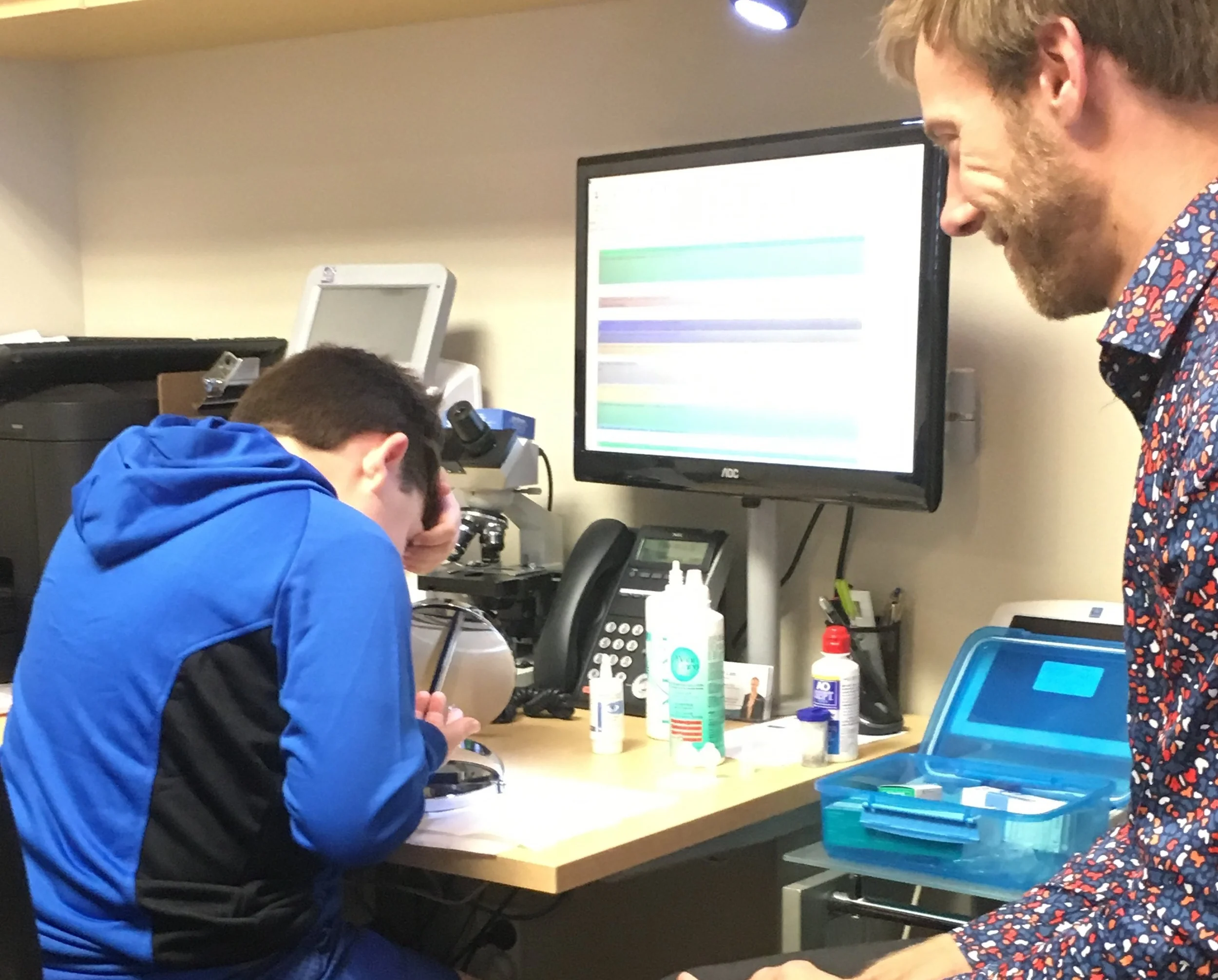 David having fun learning to insert and remove his Ortho-K contact lenses under Alex's watchful supervision.
