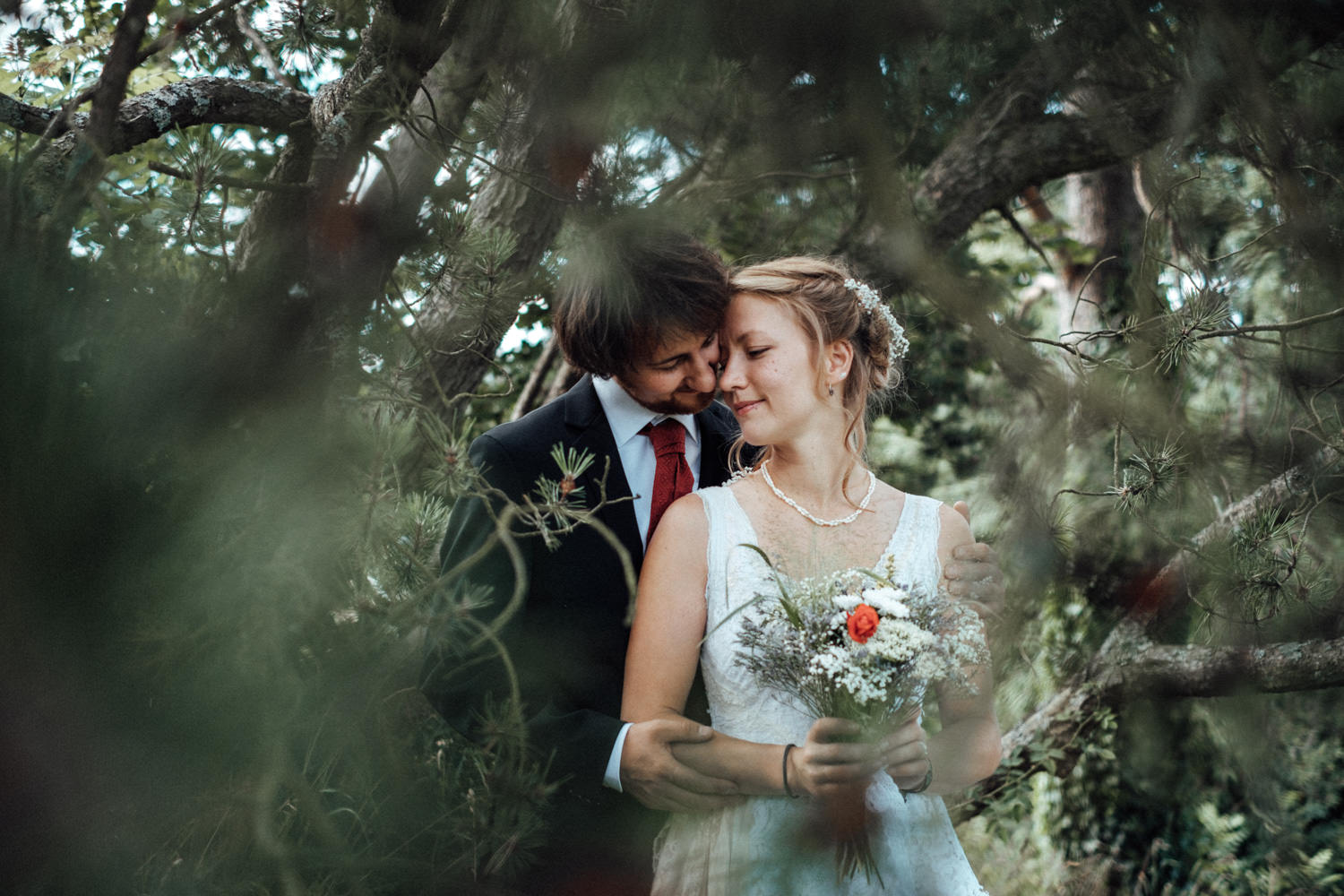 Das Hochzeitspaar inklusive natürlichem Brautstrauß mit roter Mohnblume