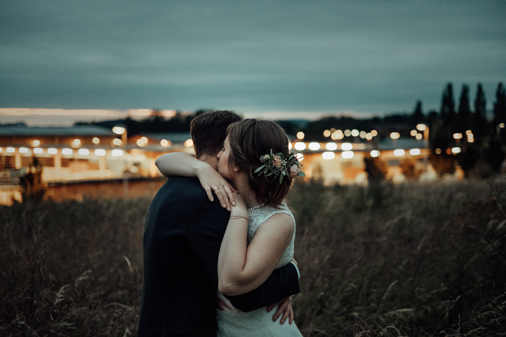 Hochzeitspaar beim Paarshooting mit tollem Sonnenuntergang und Dämmerung und Lichtern im Hintergrund.