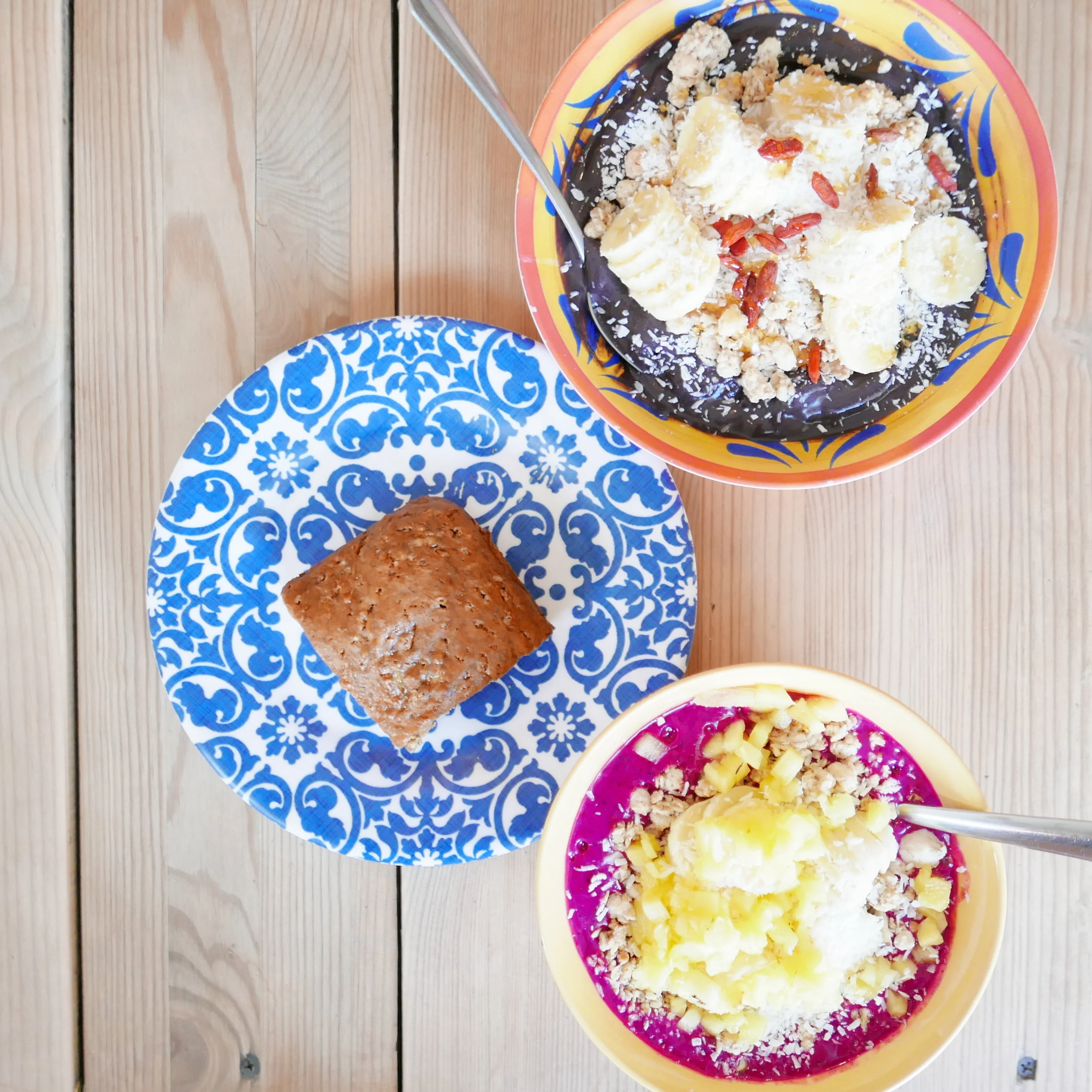 Top: Superfood Bowl - Raw acai blended with banana, spirulina and maca topped with granola, sliced banana, coconut shavings, goji berries Bottom: Dragon Bowl - Raw dragon fruit blended with banana. Topped with granola, sliced banana, pineapple and coconut shavings.