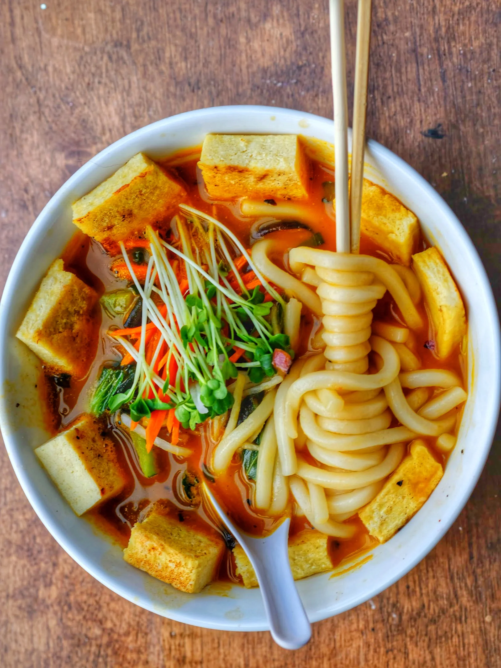 mushrooms, bok choy, fennel, shallot, jalapenos, thai basil and fresh noodles in a carrot ginger broth with daikon, pickeld carrot, sprouts