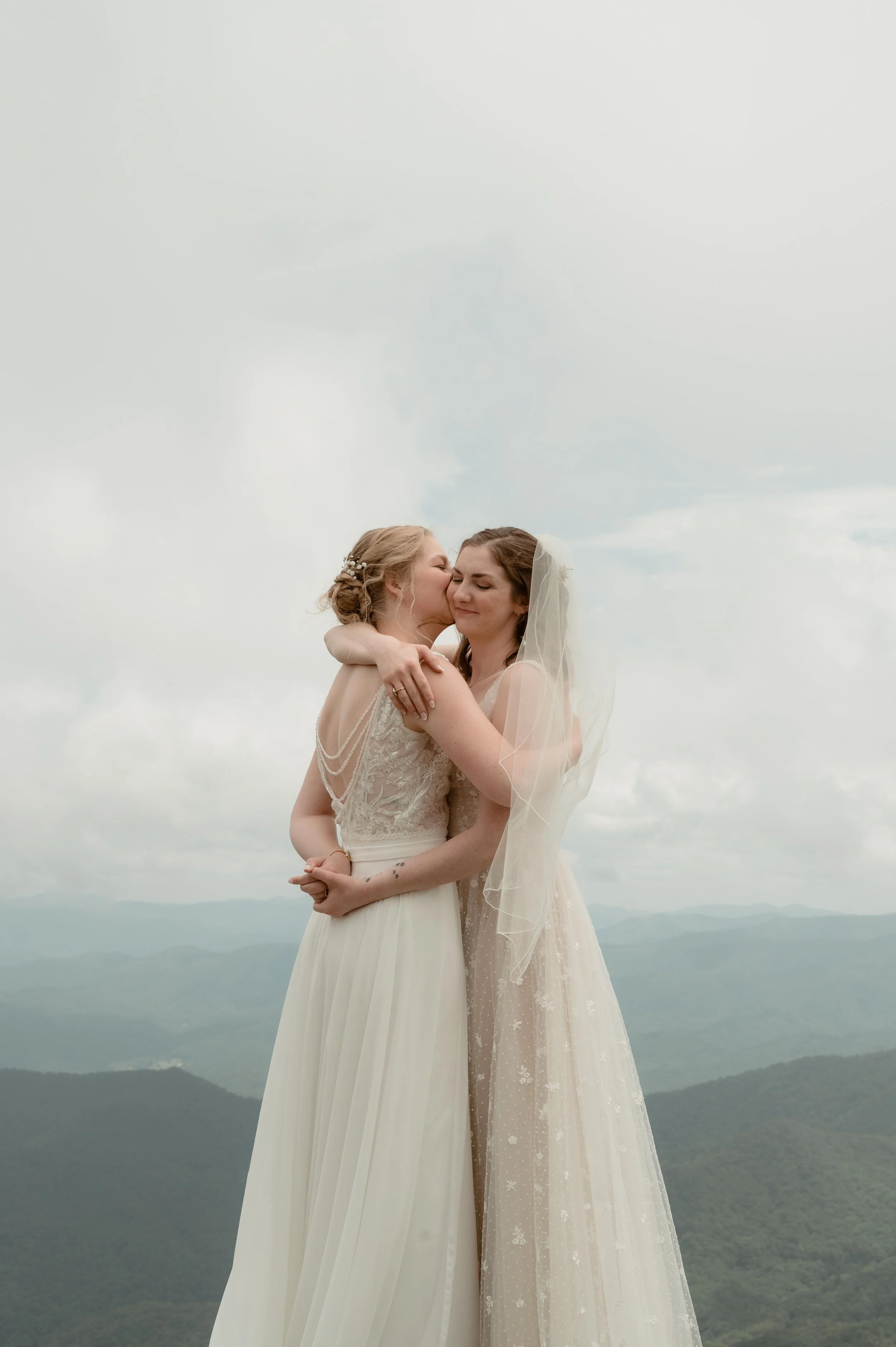 Cinematic North Carolina wedding photography two brides pose overlooking the Appalachian mountains in Nantahala, North Carolina. Cinematic Memphis wedding photographer. Moody Memphis wedding photographer. Moody North Carolina wedding photographer.
