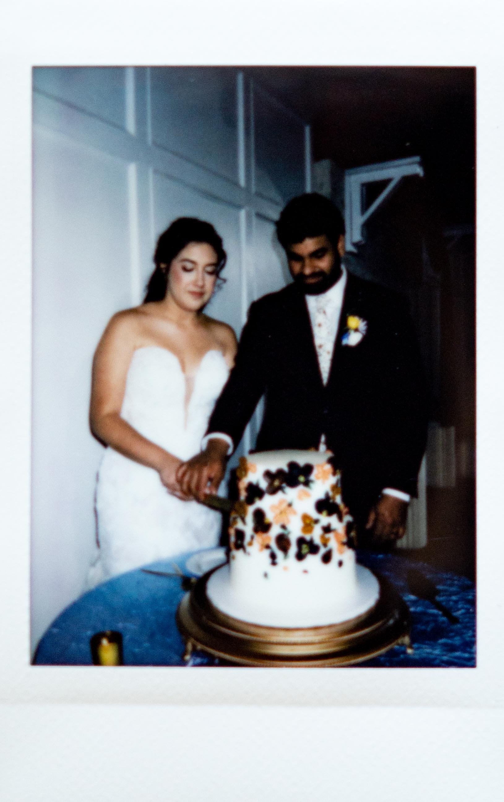 Instant film polaroid wedding photography bride and groom cutting a cake decorated with colorful floral patterned icing at Southern Grace in Memphis, Tennessee. Moody Memphis wedding photographer. Memphis film wedding photographer.