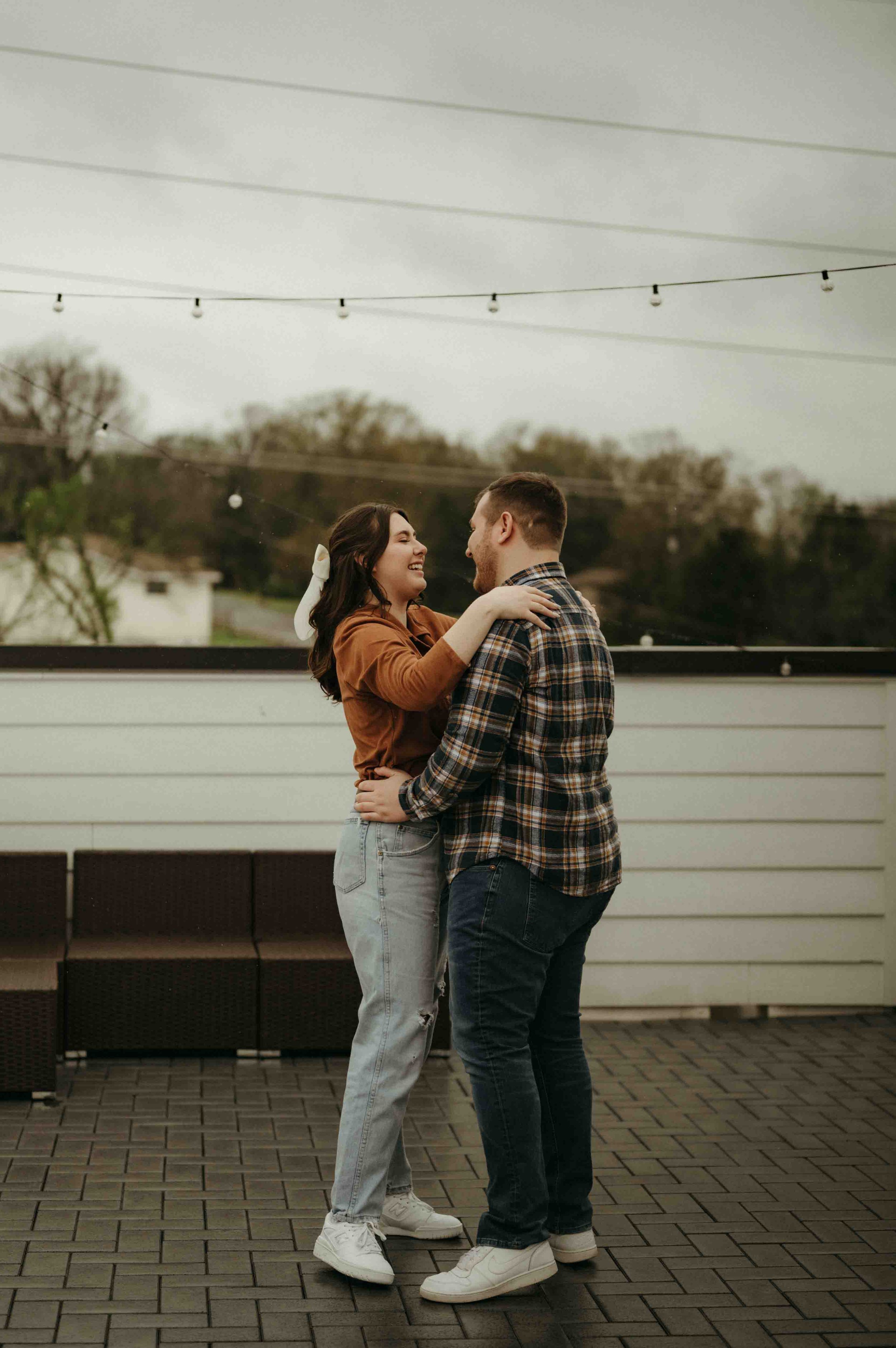 A couple dressed in orange and denim dance in the rain on a rooftop in Nashville, Tennessee.