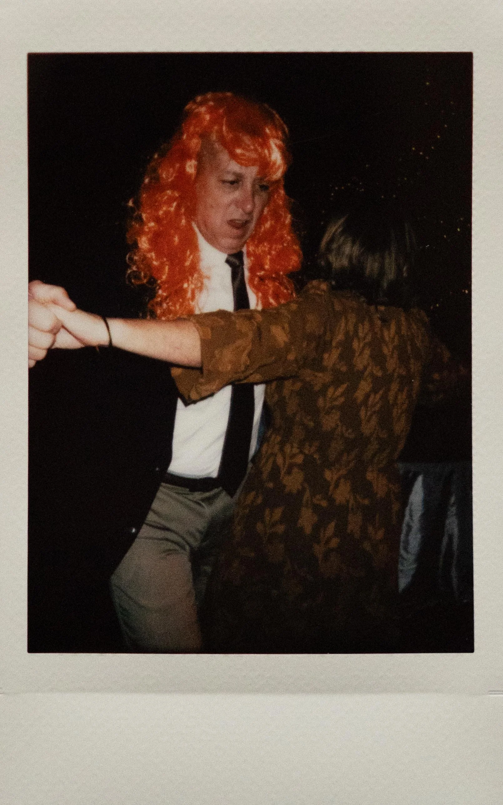 Instant film polaroid photo of a groomsman dancing in an orange wig. Wedding film photographer Memphis. Documentary wedding photographer Memphis. Moody Memphis wedding photographer.