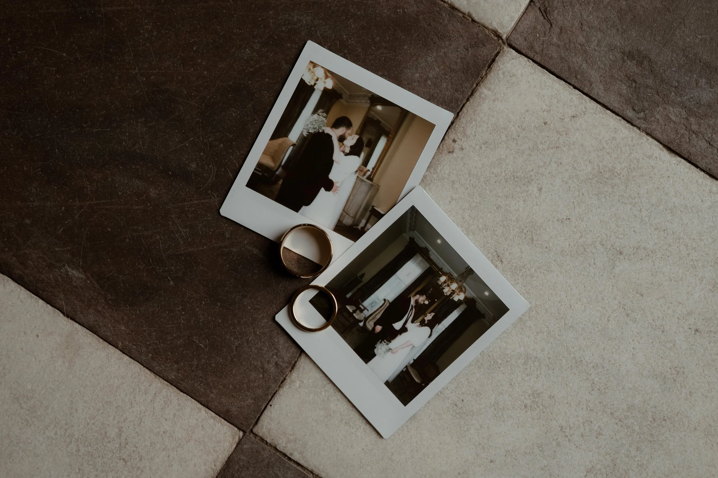 Moody wedding photography of polaroid photos and wedding rings on a black and white stone tile patio at the James Lee House in Memphis, Tennessee. Moody Memphis wedding photographer. Documentary Memphis wedding photographer.