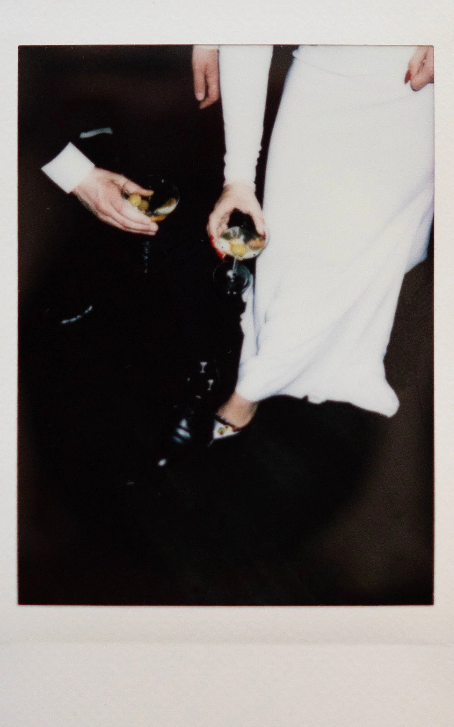 Instant film polaroid wedding photography a bride and groom holding their martinis next to their martini themed socks and shoes. Harvey House Madison Wisconsin. Moody Madison wedding photographer.