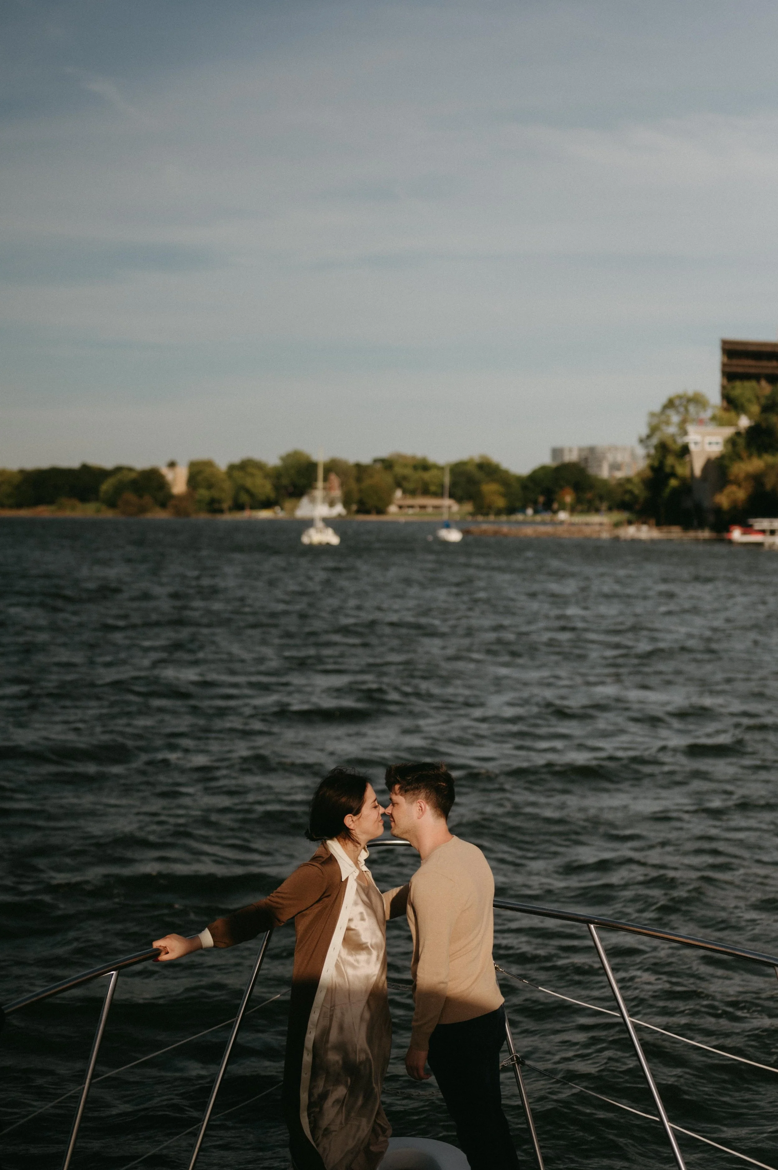 Couple posing on a yacht with Madison, Wisconsin behind them. Moody downtown wedding photographer. Documentary Madison wedding photographer.