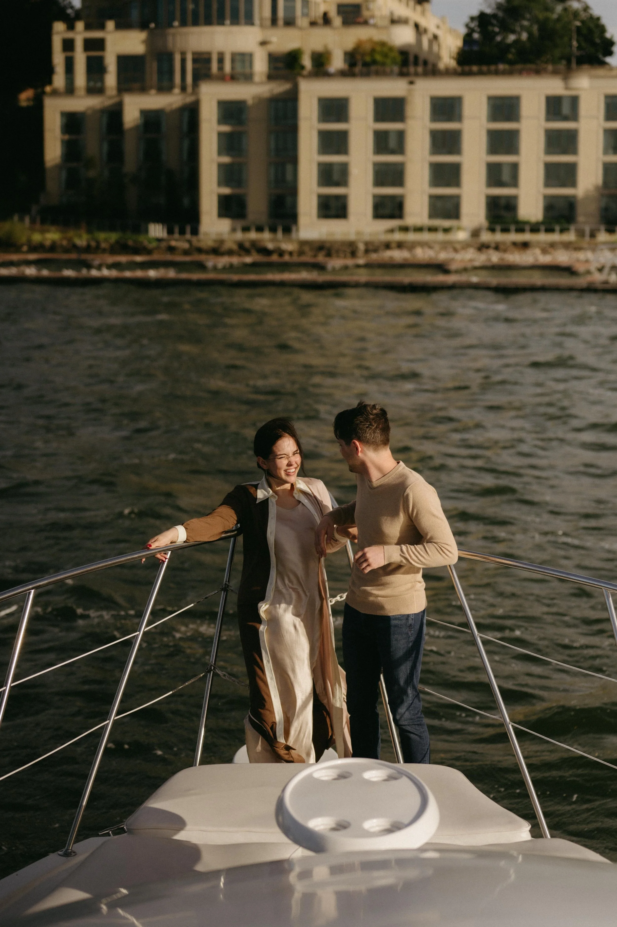 Couple posing on a yacht with Madison, Wisconsin behind them. Moody downtown wedding photographer. Documentary Madison wedding photographer.
