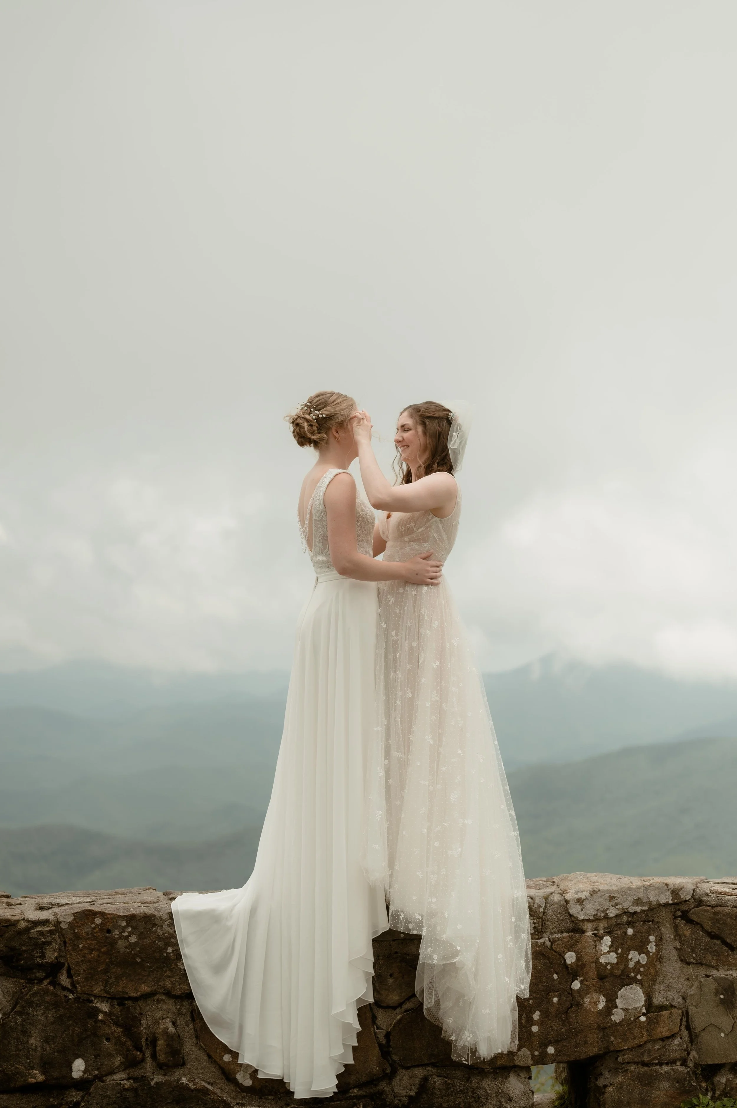 Moody North Carolina wedding photographer two brides embrace on a mountaintop overlooking the Appalachian mountains in Nantahala North Carolina. Moody Memphis wedding photographer. Cinematic North Carolina wedding photographer.