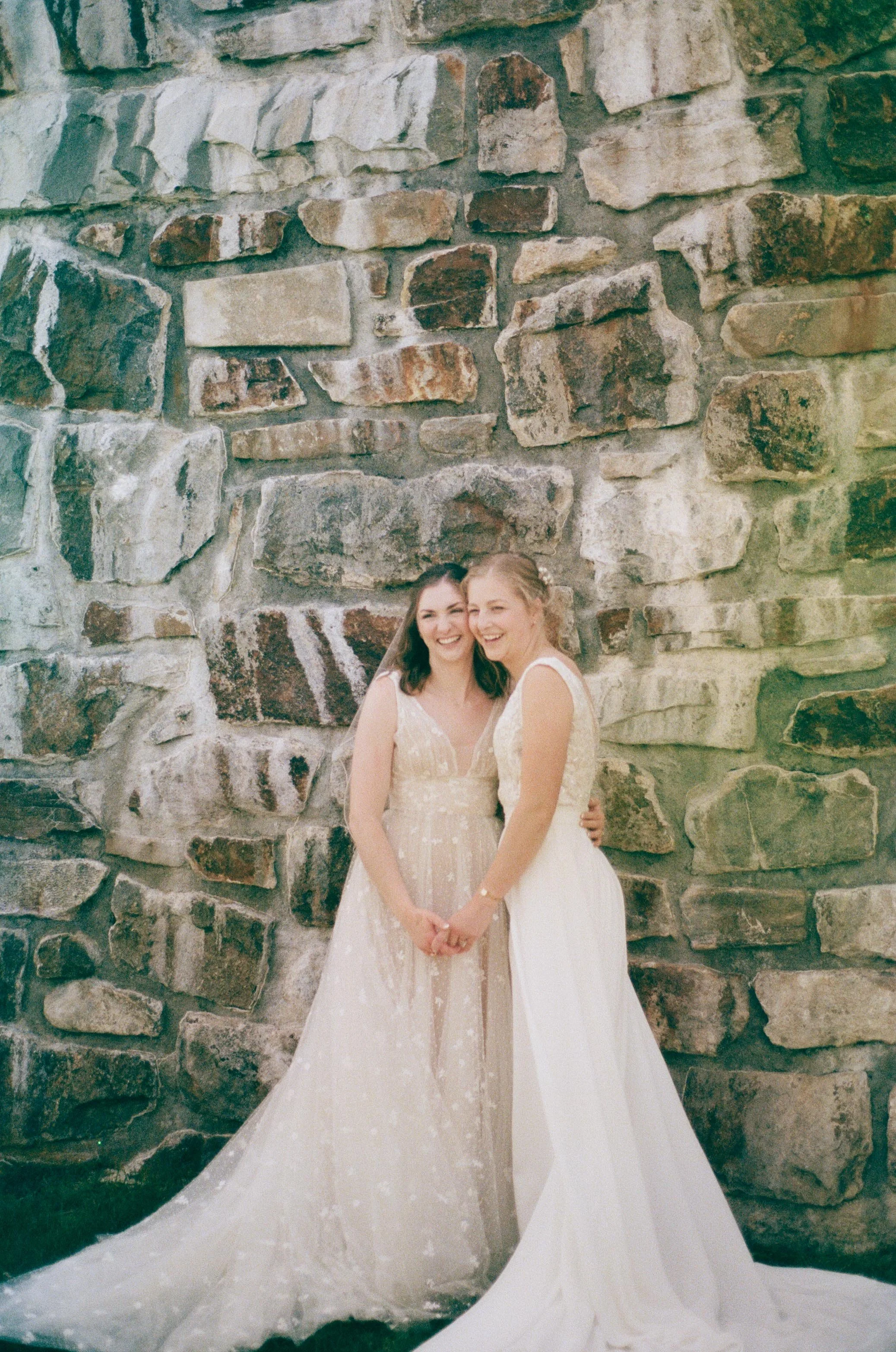 North Carolina film wedding photographer two brides pose in front of a stone wall in Nantahala, North Carolina. Memphis film wedding photographer.