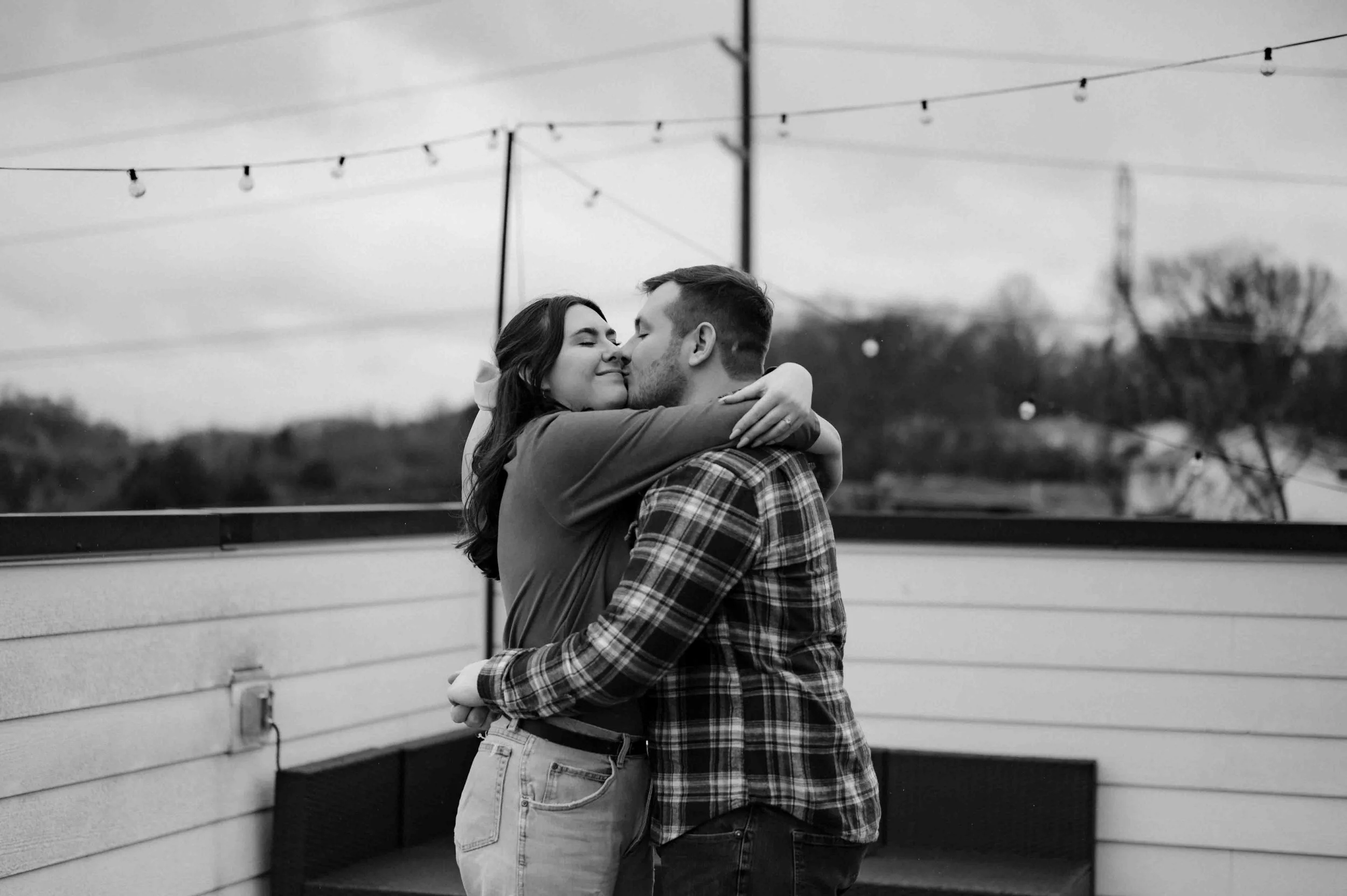 Black and white photo of a couple kissing and dancing on a rooftop in the rain in Nashville, Tennessee. Nashville wedding photographer.