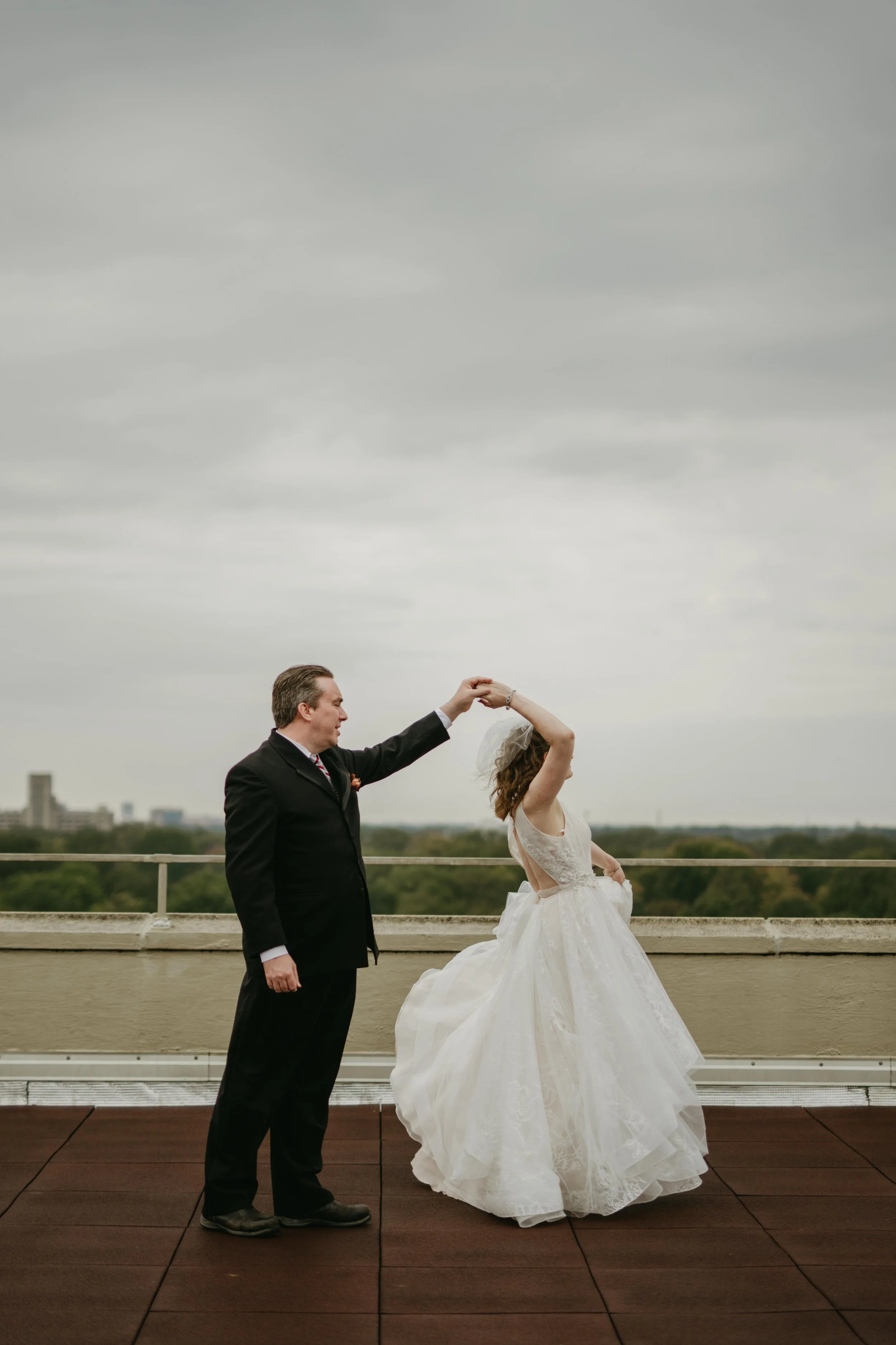 Moody Memphis wedding photographer a bride and groom pose on a rooftop with a view of the downtown Memphis skyline. Memphis Documentary wedding photographer. Cinematic Memphis wedding photographer.