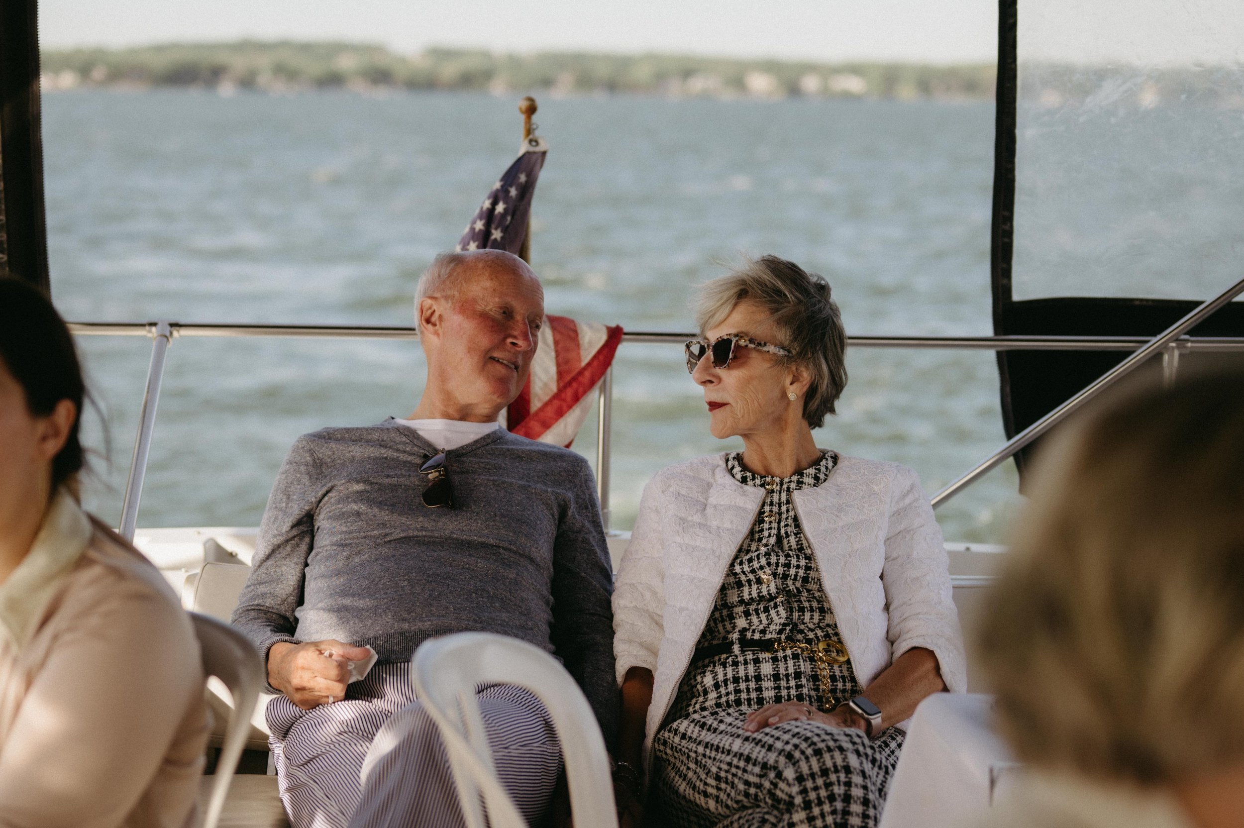 Wedding guests relax on a yacht during a welcome dinner cruise on Lake Mendota in Madison, Wisconsin. Moody Madison wedding photographer. Documentary Madison wedding photographer.