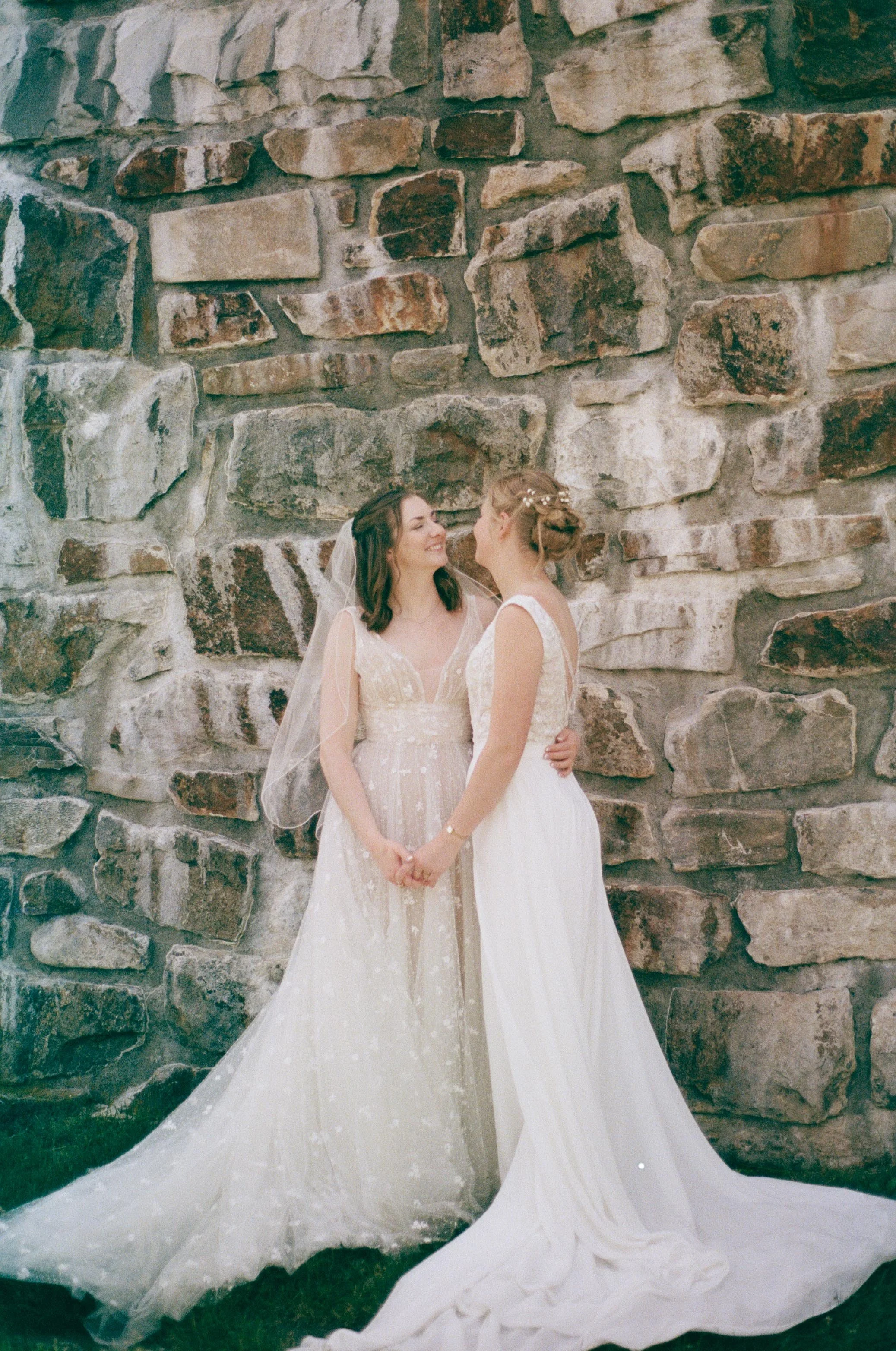 North Carolina film wedding photographer two brides pose in front of a stone wall in Nantahala, North Carolina. Memphis film wedding photographer.