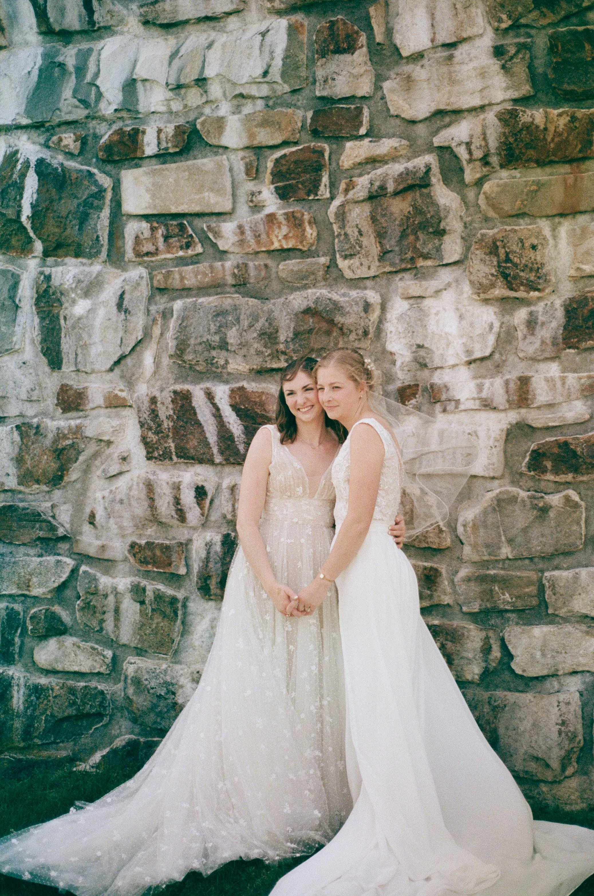 North Carolina film wedding photographer two brides pose in front of a stone wall in Nantahala, North Carolina. Memphis film wedding photographer.