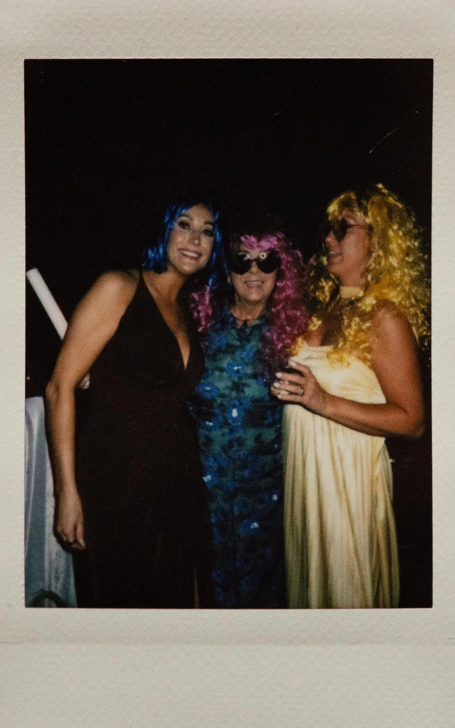 Instant film polaroid wedding photography of wedding guests in a blue wig and black dress, purple wig and blue dress, and yellow wig and yellow dress at the Memphis Botanic Garden in Memphis, Tennessee. Moody Memphis Wedding photographer.