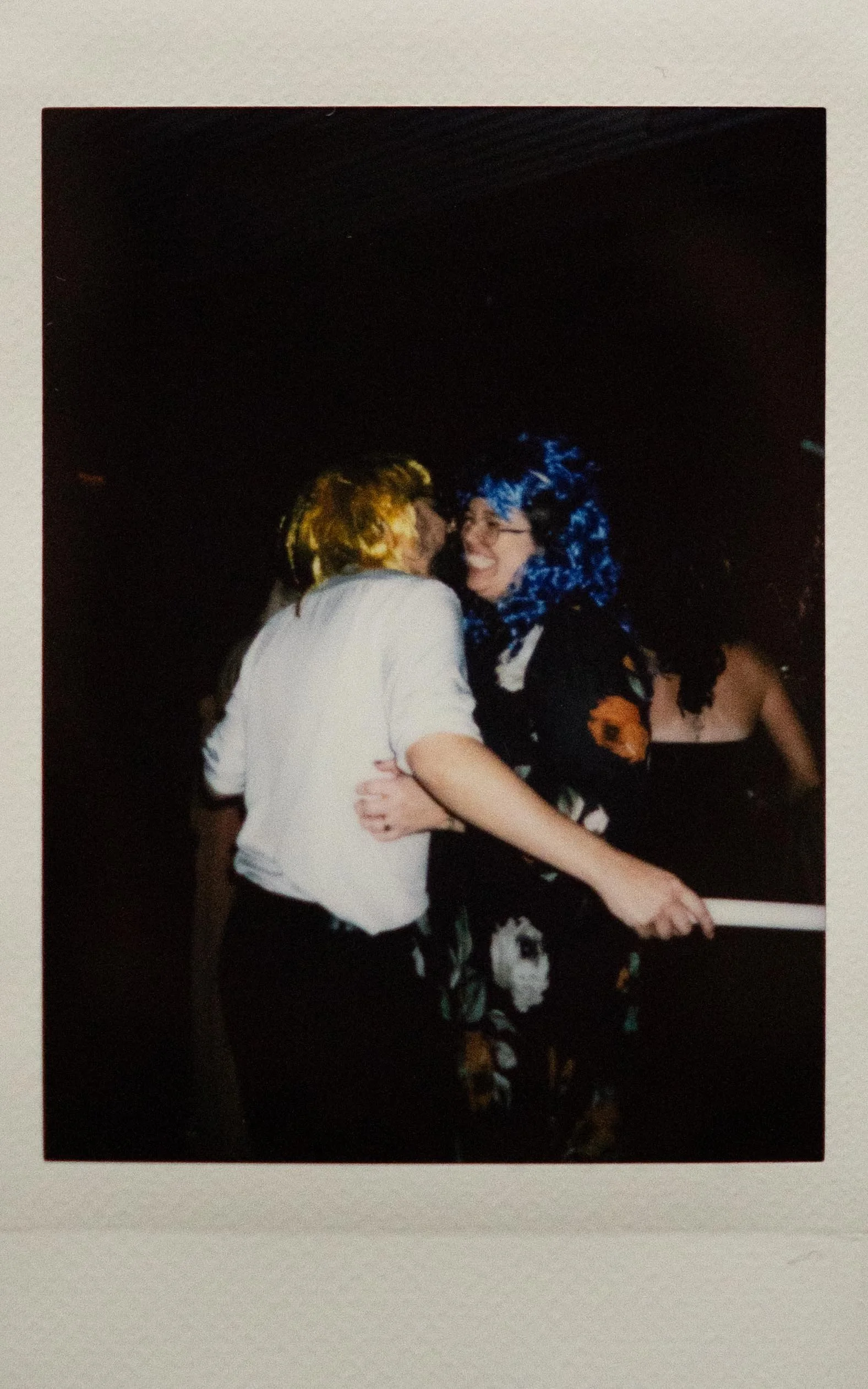 Instant film polaroid wedding photography of two guests in a yellow wig and a blue wig dancing at the Memphis Botanic Garden in Memphis, Tennessee. Moody Memphis wedding photographer. Memphis documentary wedding photographer.