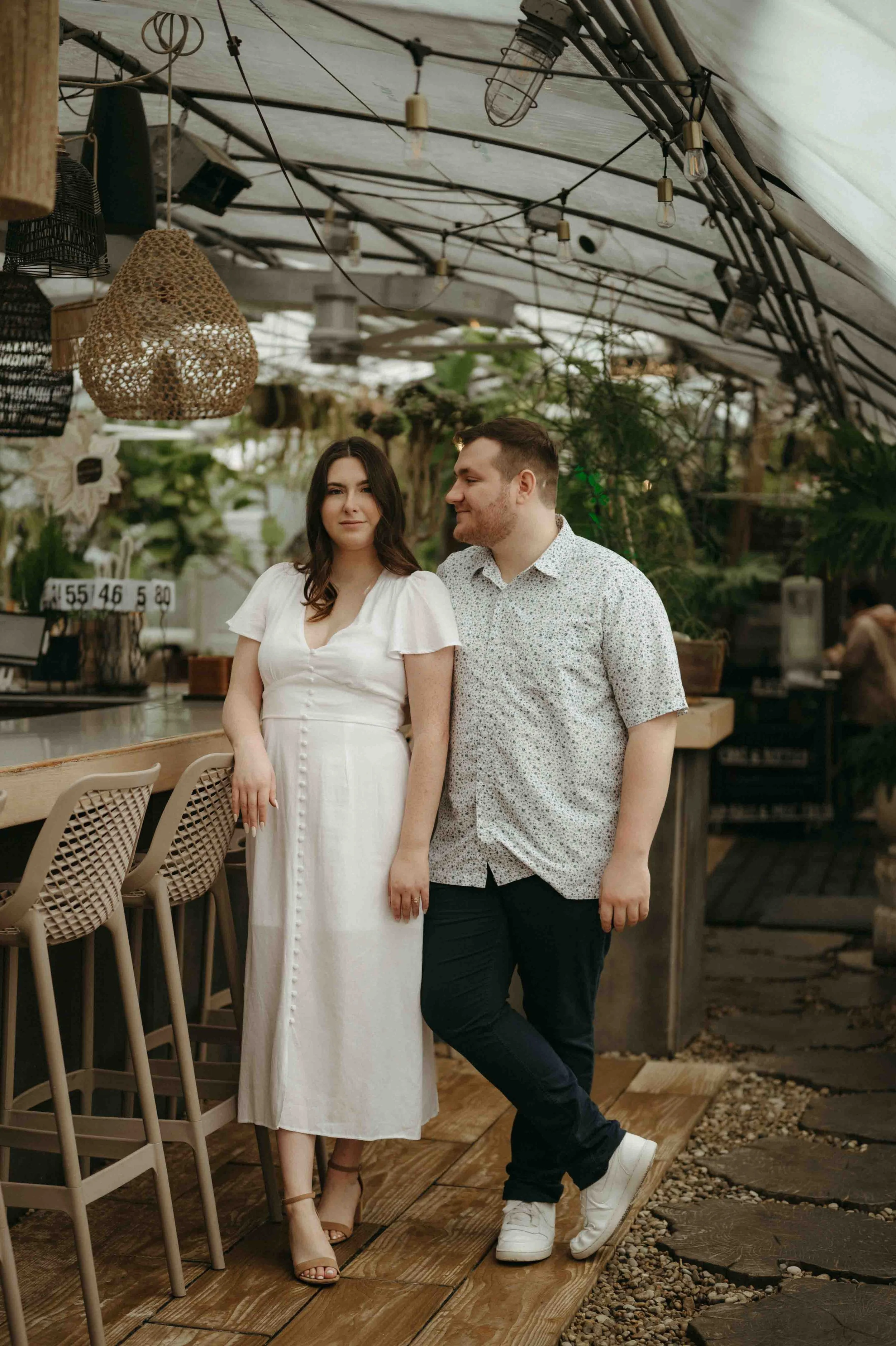 Couple dressed in white and blue, posing in an editorial style against a bar inside the Greenhouse Bar in Nashville, Tennessee.