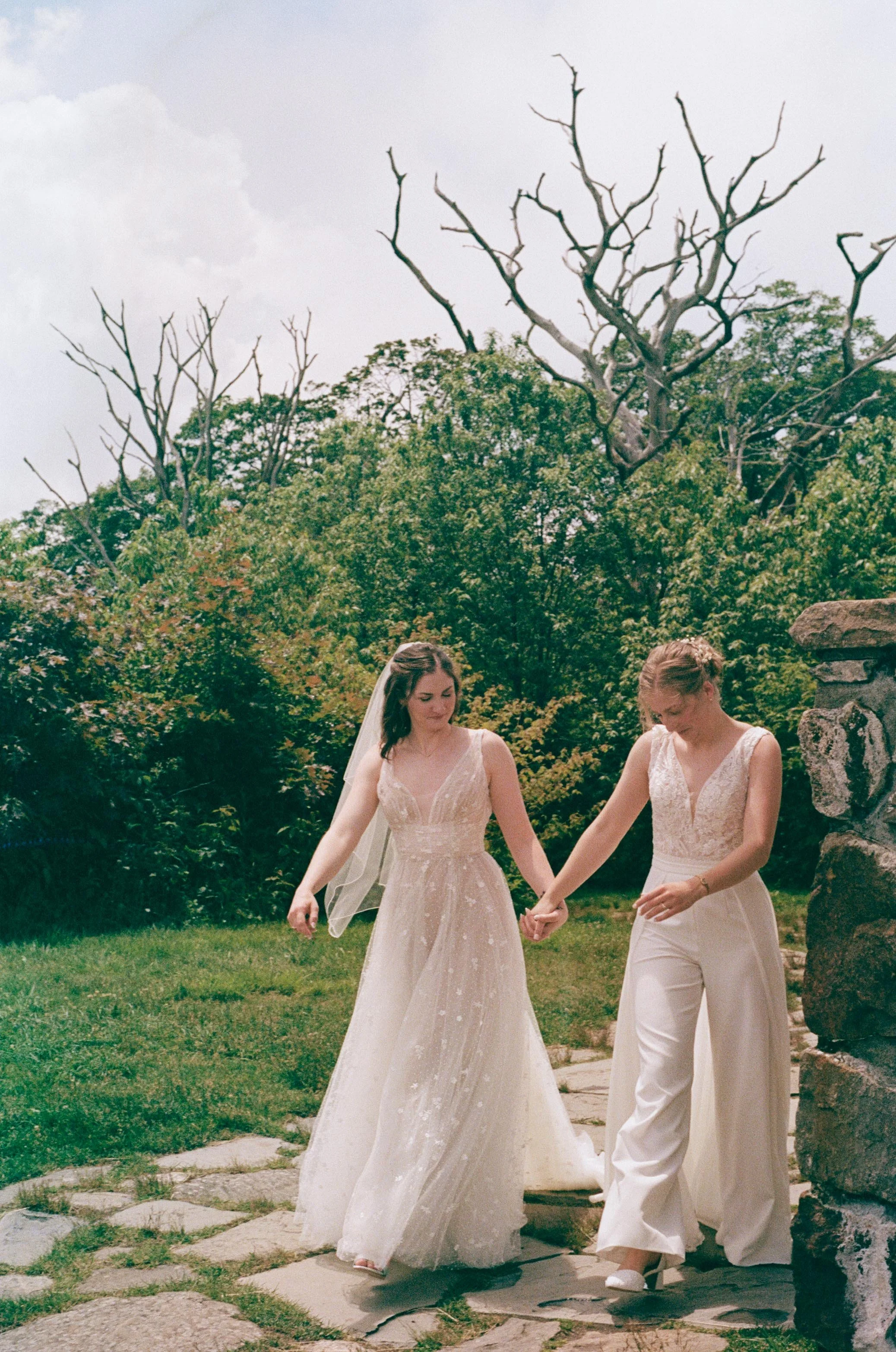 North Carolina film wedding photographer two brides walk along a stone path in Nantahala, North Carolina. Memphis film wedding photographer.