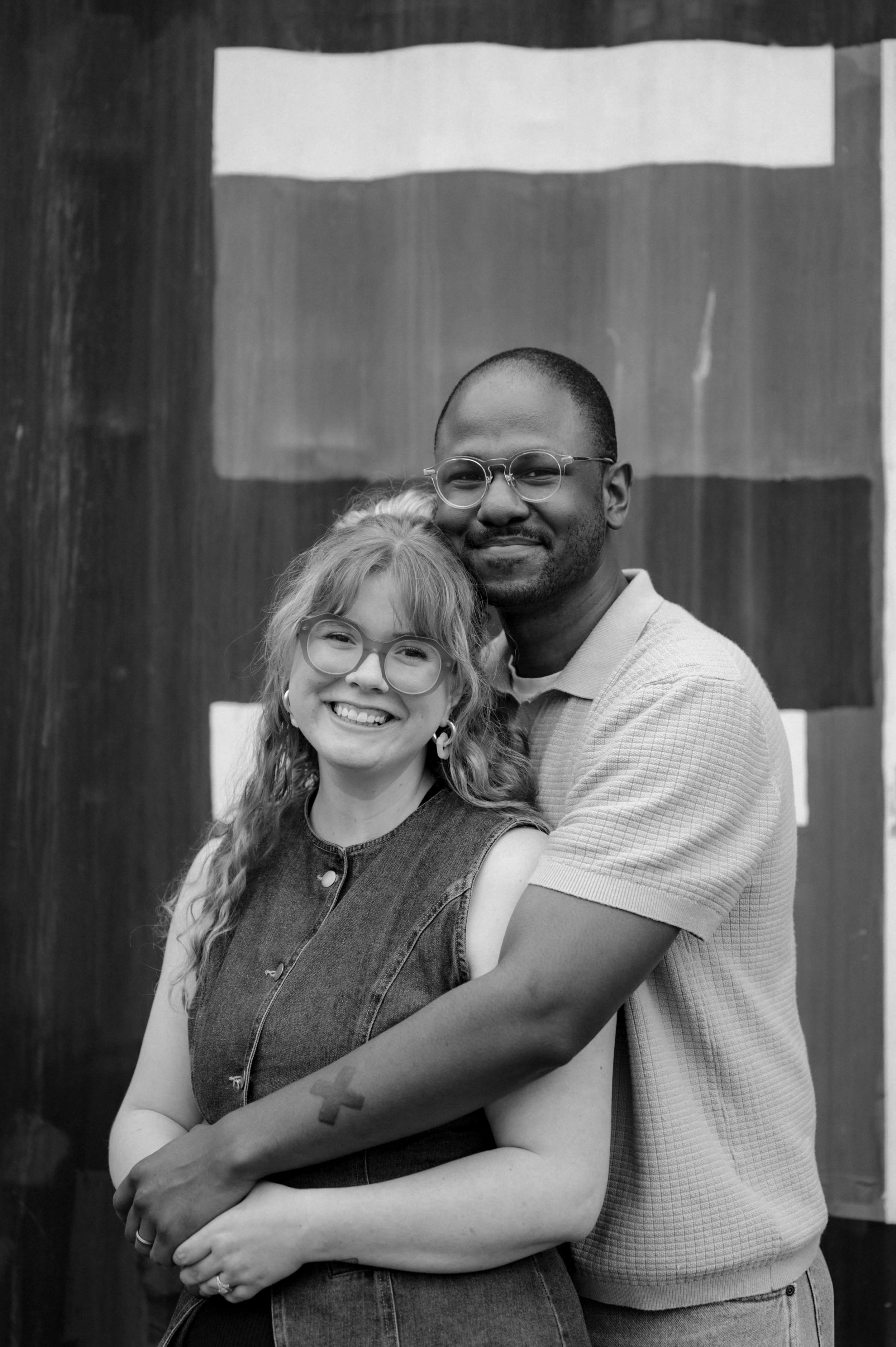 Black and white photo of a couple smiling and embracing in front of a mural in Midtown Memphis, Tennessee.