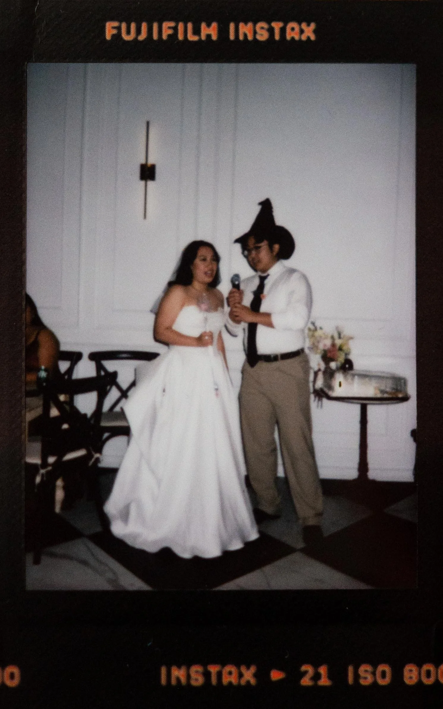 Instant film polaroid wedding photography of a bride and guest singing karaoke with props from Wicked at the Parisian in Huntsville, Alabama. Moody Huntsville wedding photographer. Huntsville film wedding photographer. Documentary Huntsville wedding