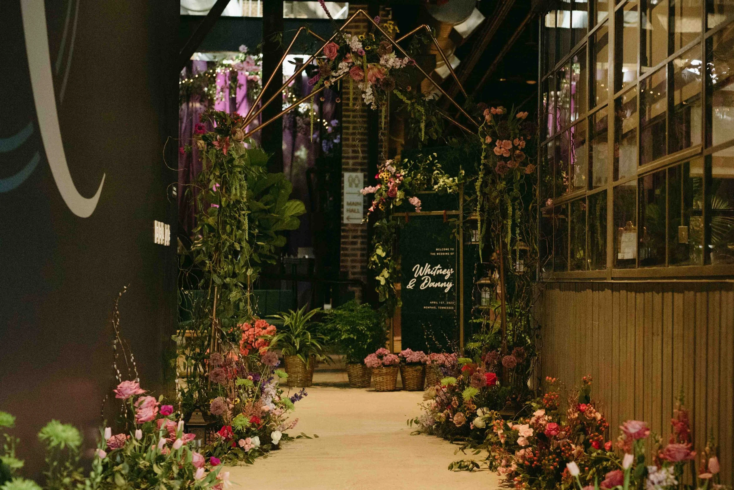 Entryway into The Kent in downtown Memphis, Tennessee, lined with baskets of pink and red flowers and greenry.