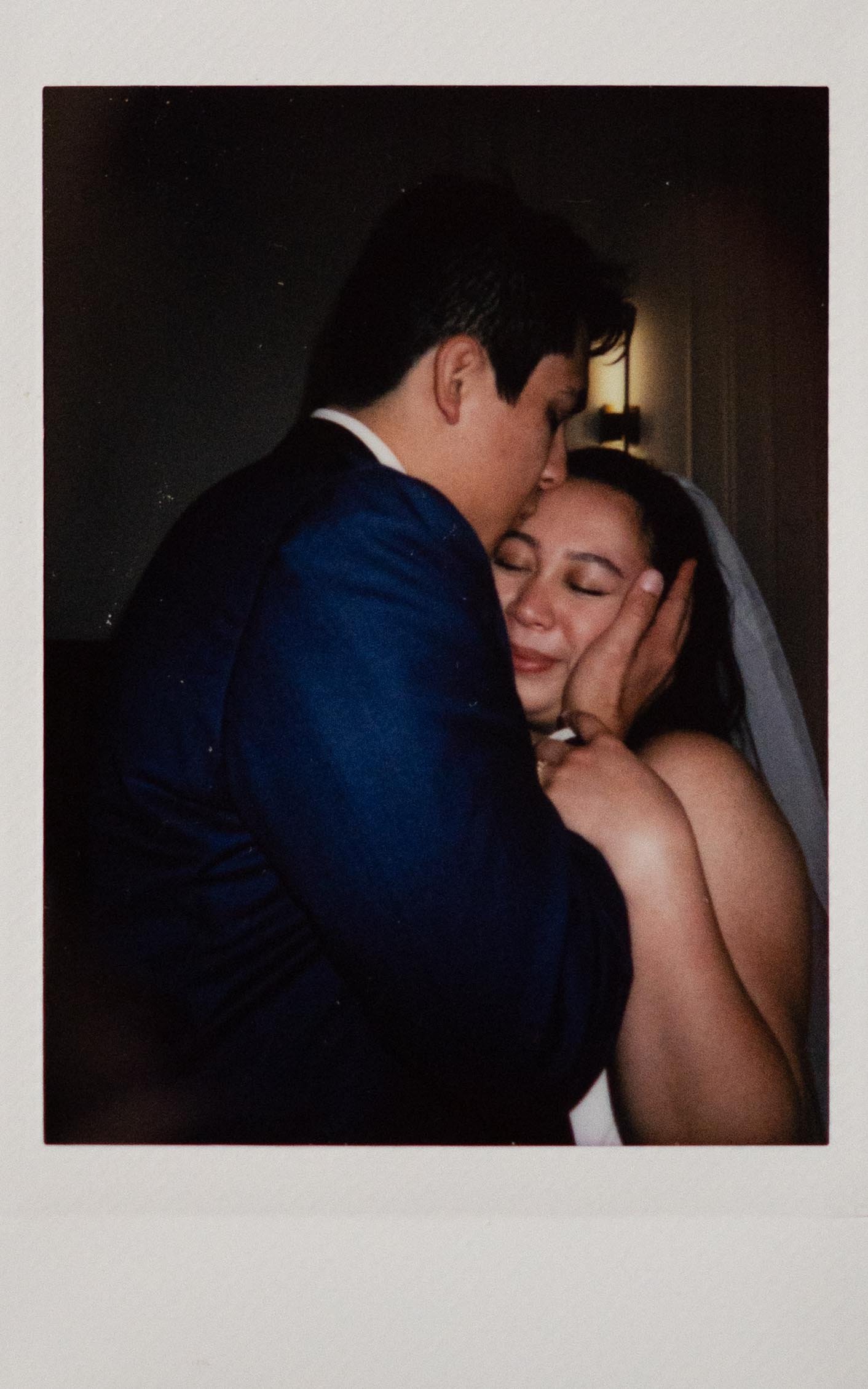 Polaroid instant film wedding photography a groom hold's his bride's faces and kisses her forehead in the Parisian in Huntsville, Alabama. Moody Huntsville wedding photographer. Documentary Huntsville wedding photographer. Forehead kiss wedding photo