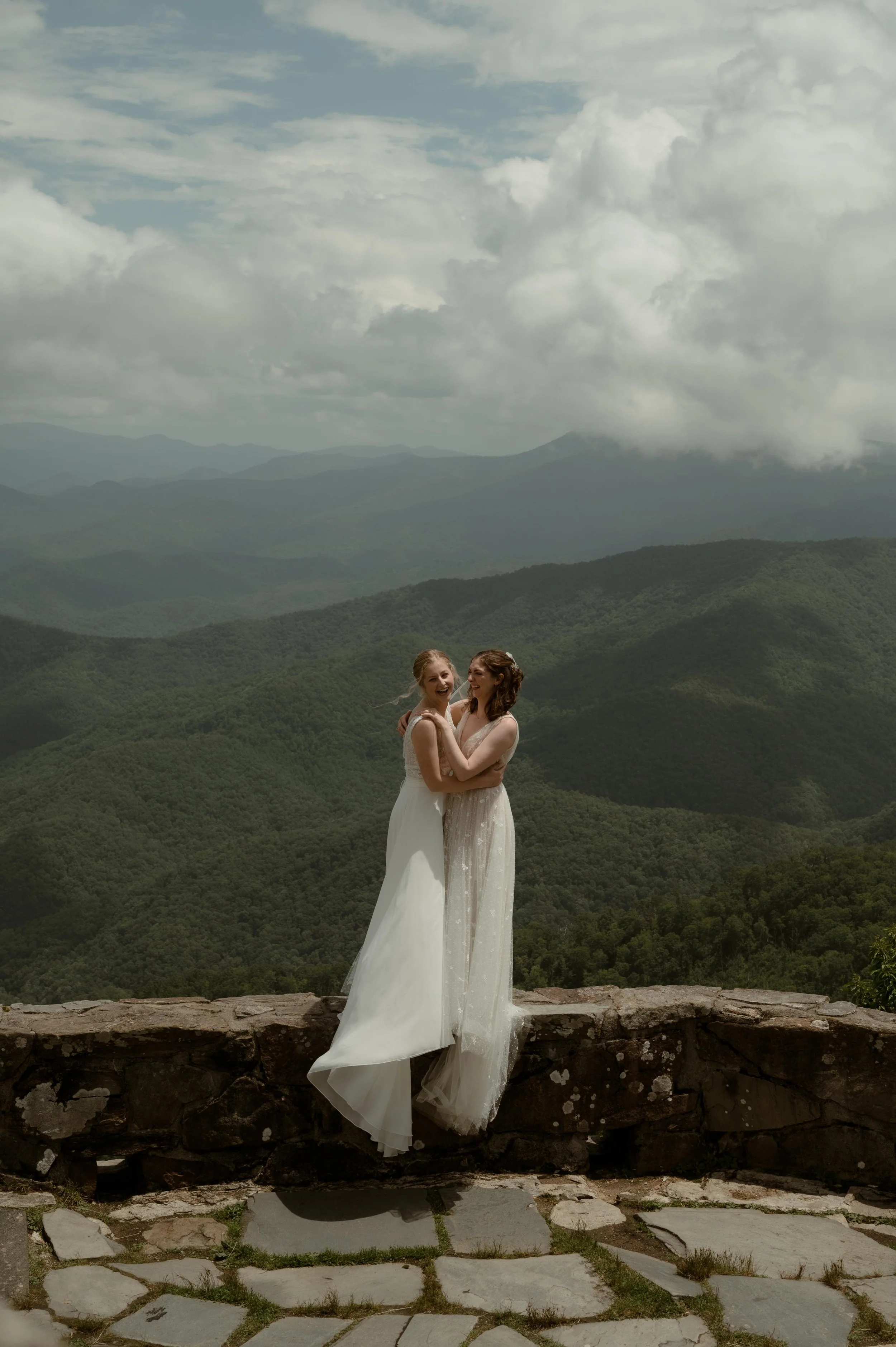 Cinematic North Carolina wedding photography two brides pose overlooking the Appalachian mountains in Nantahala, North Carolina. Cinematic Memphis wedding photographer. Moody Memphis wedding photographer. Moody North Carolina wedding photographer.