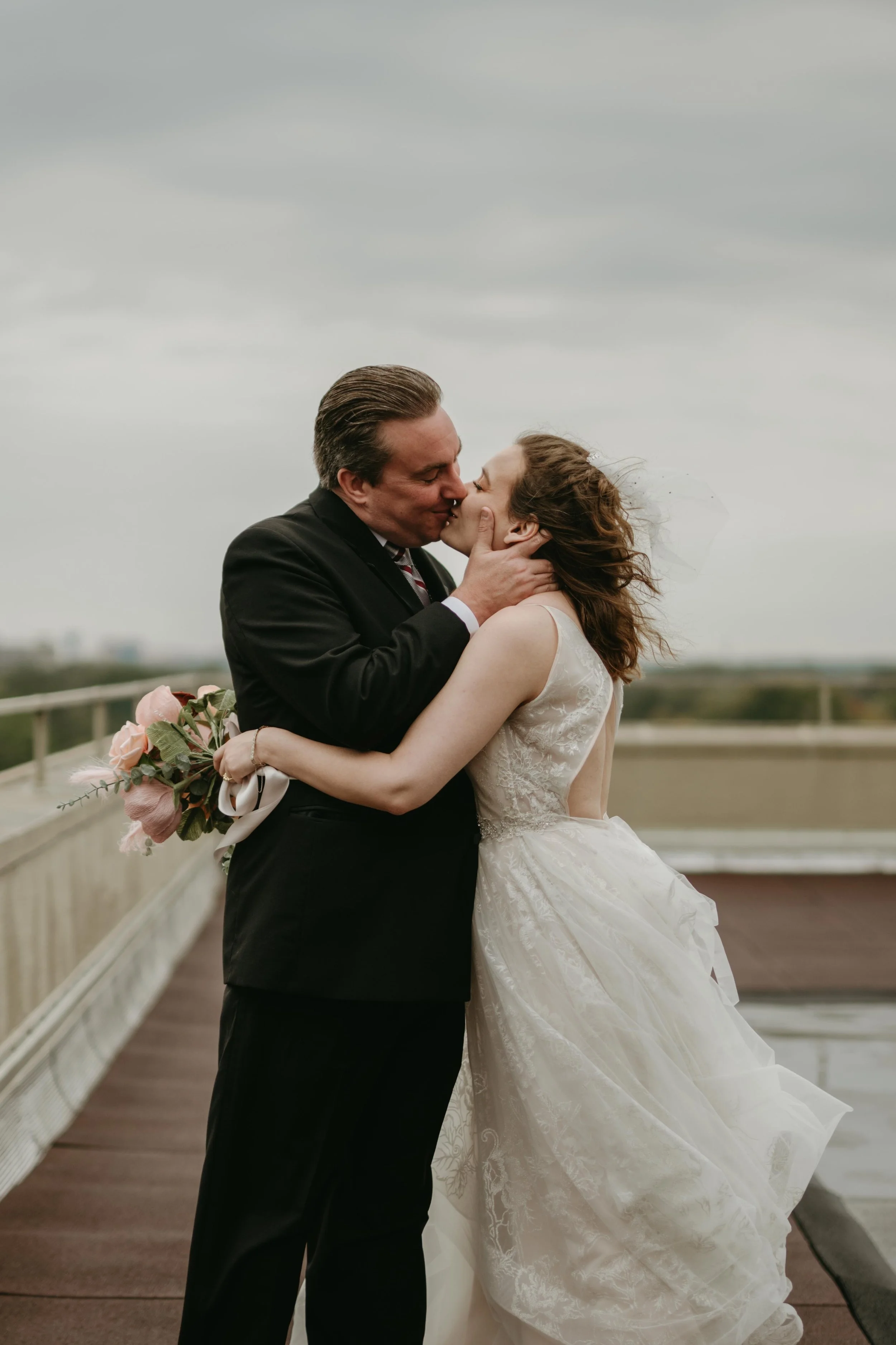 Moody Memphis wedding photographer a bride and groom pose on a rooftop with a view of the downtown Memphis skyline. Memphis Documentary wedding photographer. Cinematic Memphis wedding photographer.