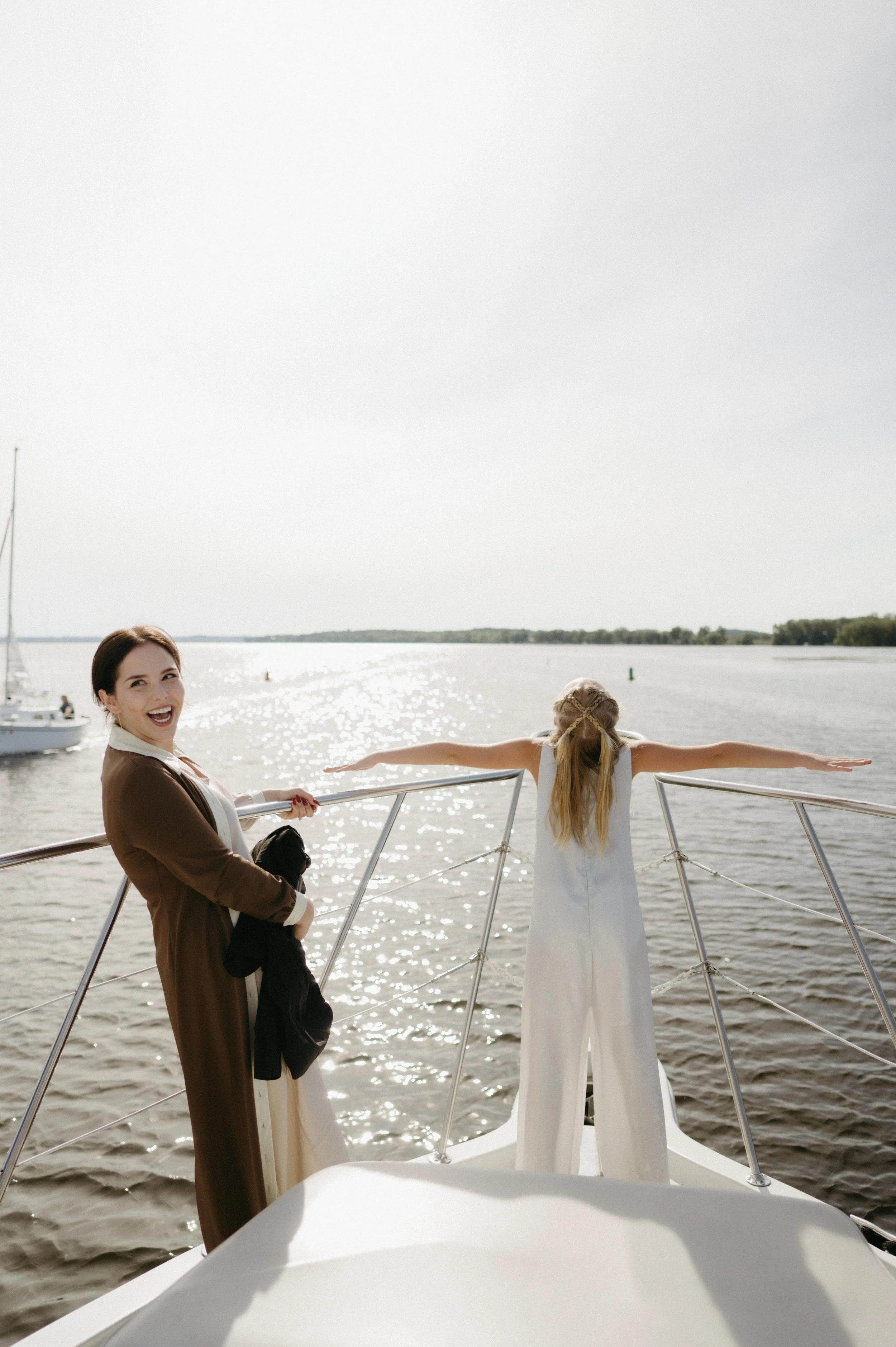 The bride and the junior bridesmaid laughing and recreating the famous Titanic boat pose. Moody Madison wedding photographer. Documentary Madison wedding photographer.