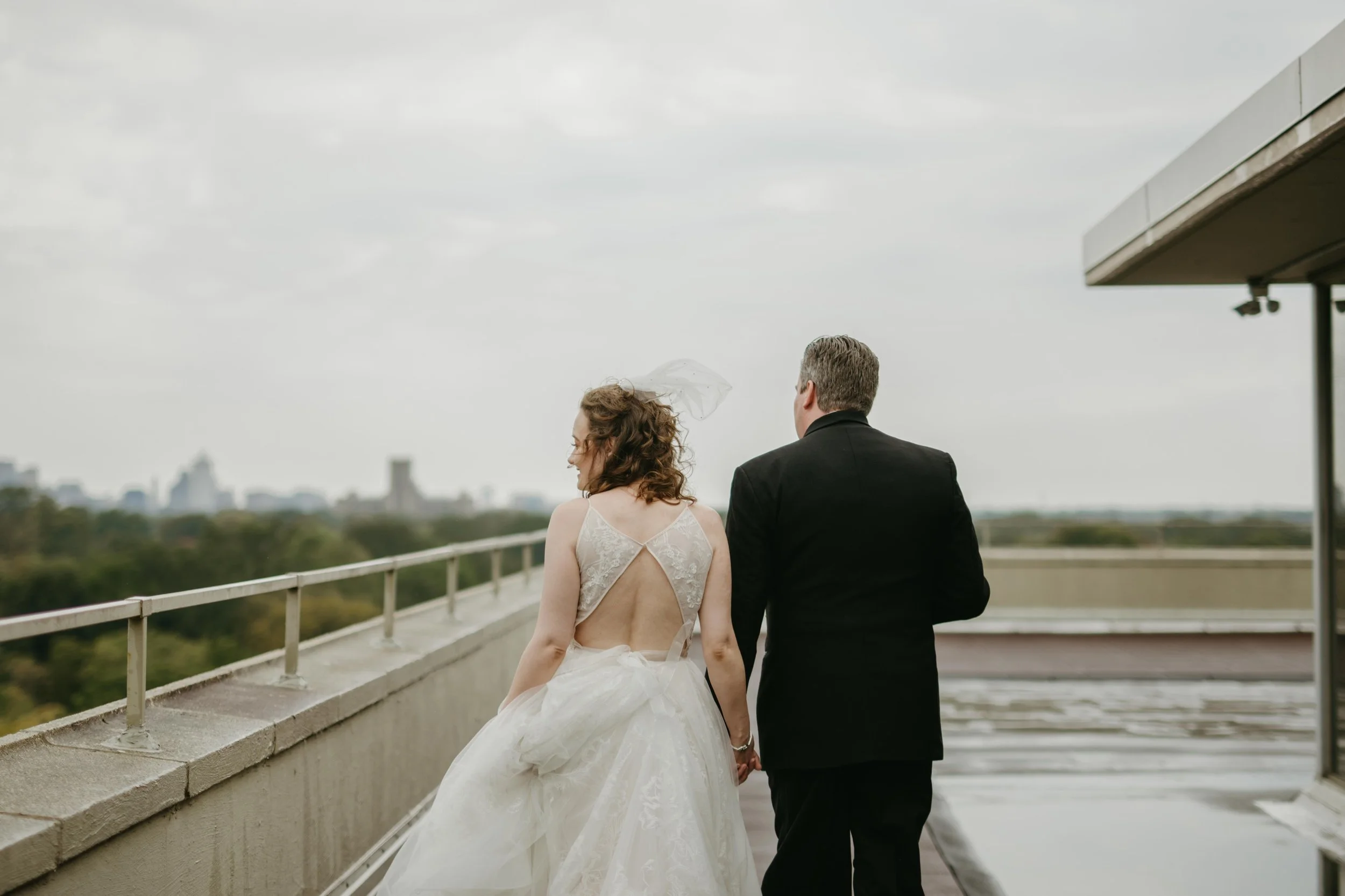 Moody Memphis wedding photographer a bride and groom pose on a rooftop with a view of the downtown Memphis skyline. Memphis Documentary wedding photographer. Cinematic Memphis wedding photographer.
