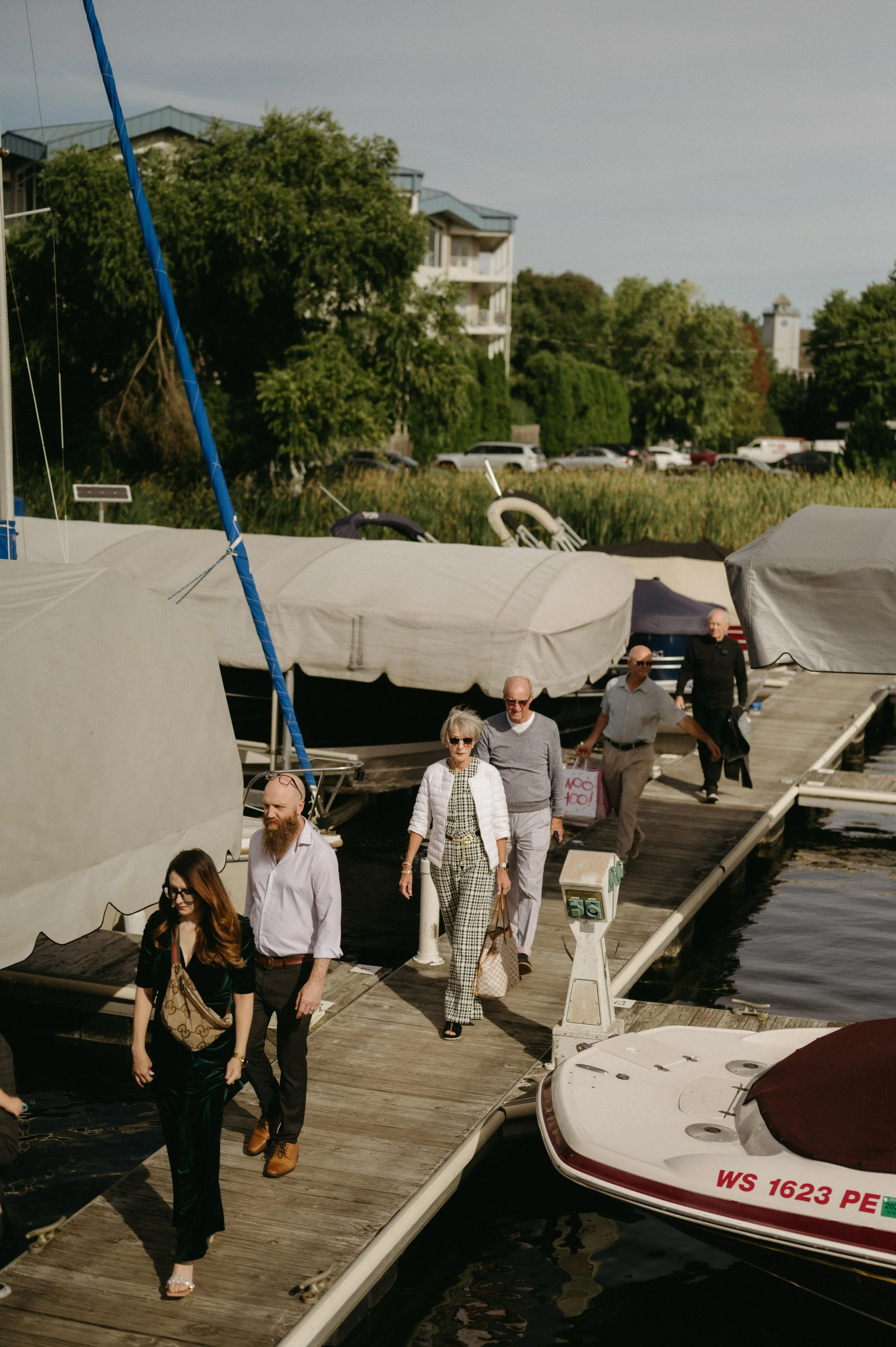 Guests walk the docks outside Madison, Wisconsin, to begin a rehearsal dinner cruise around Lake Mendota. Moody Madison wedding photographer. Documentary Madison wedding photographer.