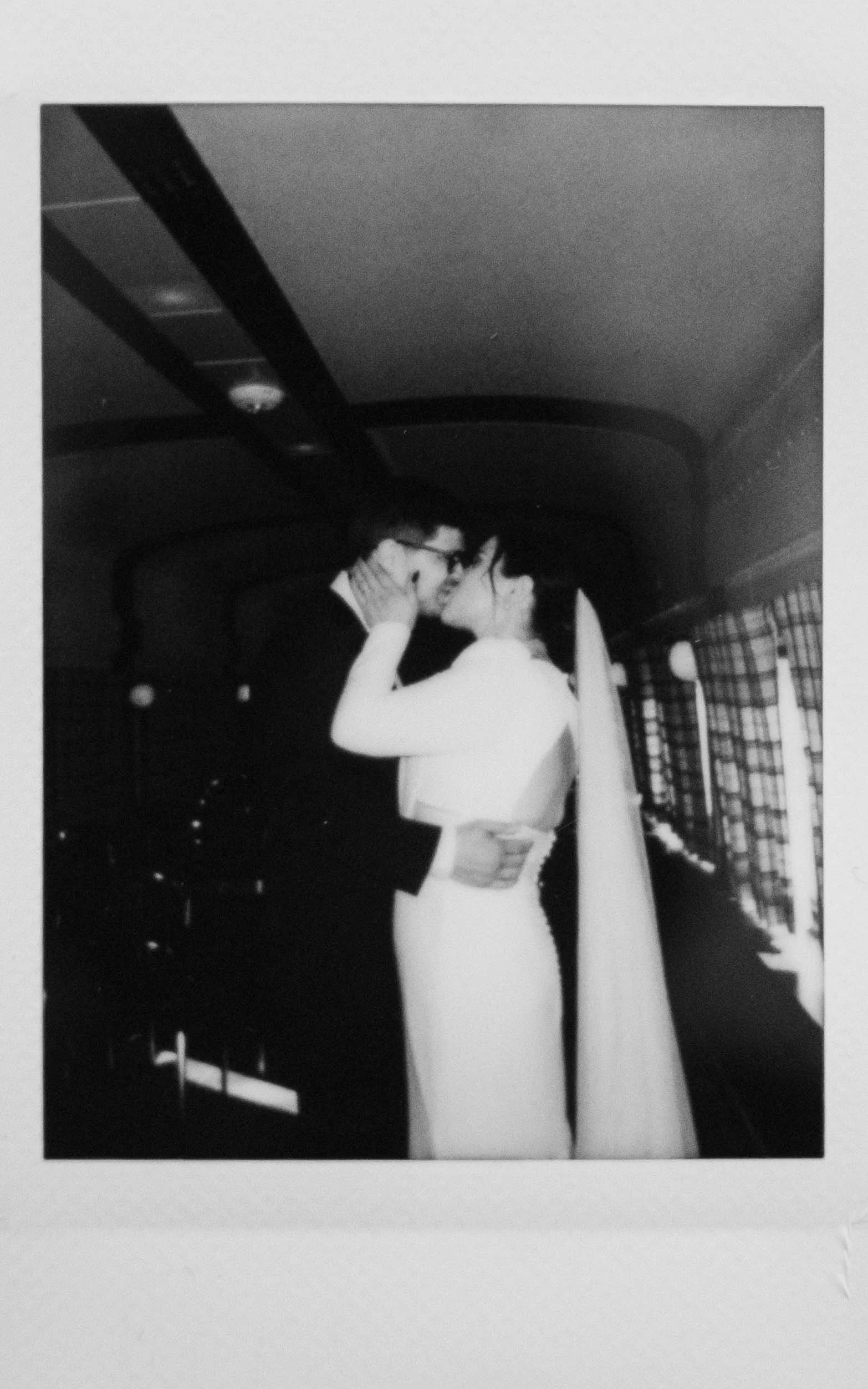Instant film polaroid wedding photography a bride and groom embracing and kissing during their first look in the train car at The Harvey House Restaurant in Madison, Wisconsin. Moody Madison wedding photographer. Madison film wedding photographer.
