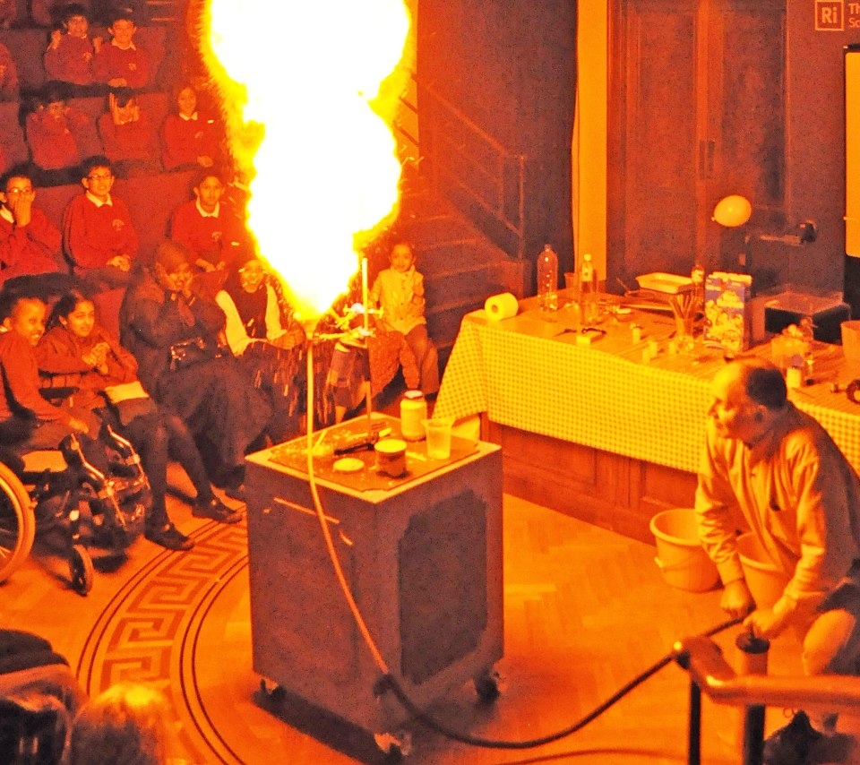 Notice, in the previous paragraph, how little effort Faraday makes to discourage his audience of children from experimenting at home with gunpowder! Faraday's next demonstration uses lycopodium powder, an extremely fine powder consisting of club-moss spores. The photograph, taken at the Royal Institution, shows my own version of the same demonstration, but instead using custard powder which is basically cornflour. I have presented my Exploding Custard show to children at the Royal Institution a number of times, standing exactly where Michael Faraday stood. 
