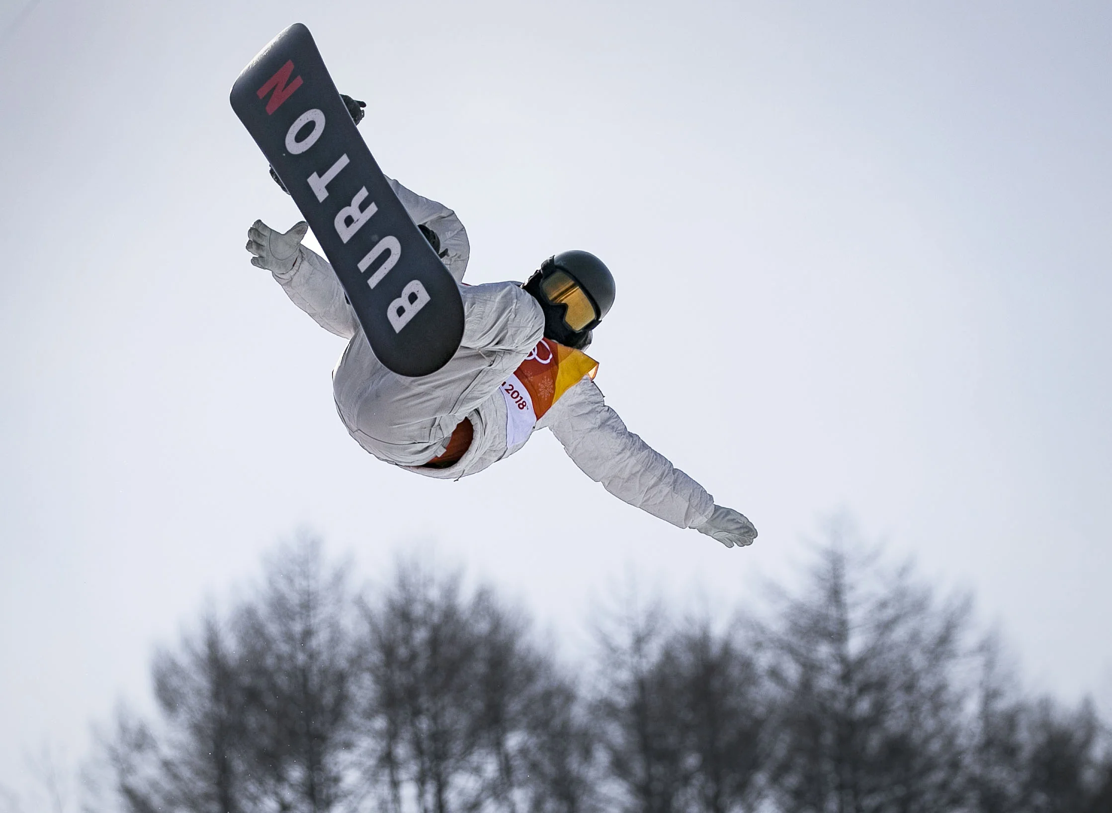 Two time Olympic champion, halfpipe snowboarder Shaun White, reaches for his second jump at Phoenix Snow Park, PyeongChang, Feb. 13, for his second run scoring a 98.50, leading his way to the halfpipe finals. White will compete tomorrow against 11 other snowboarders to hold his position, in hopes to win his third Olympic gold medal.