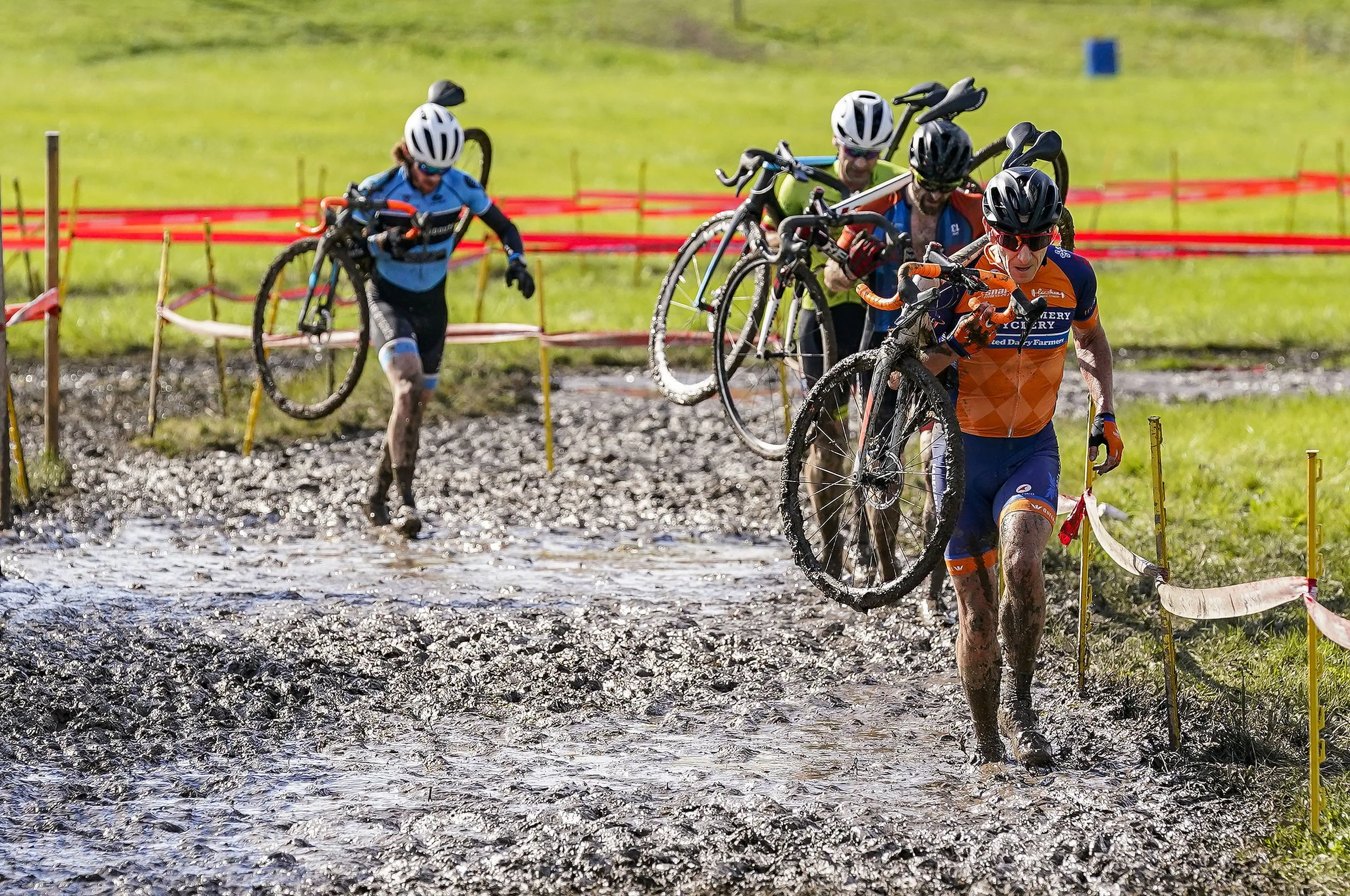  Cyclists carry their bikes through deep mud during the Major Taylor Cross Cup race on Sunday, Oct. 31, 2021 at the Indy Cycloplex on Cold Spring Road, in Indianapolis. 