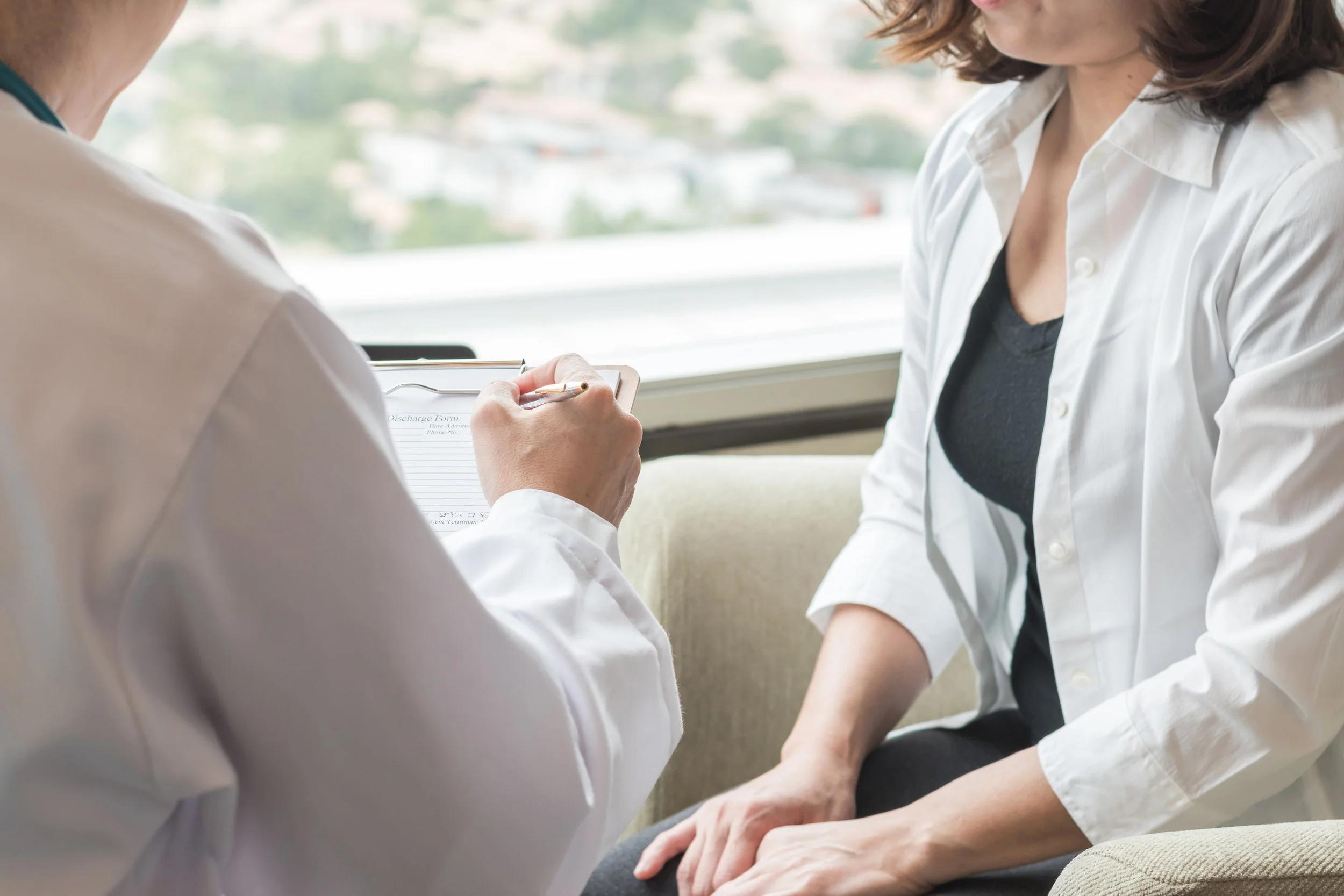 Male doctor consulting with female patient in a family practice clinic about healthcare services, treatments, and procedures
