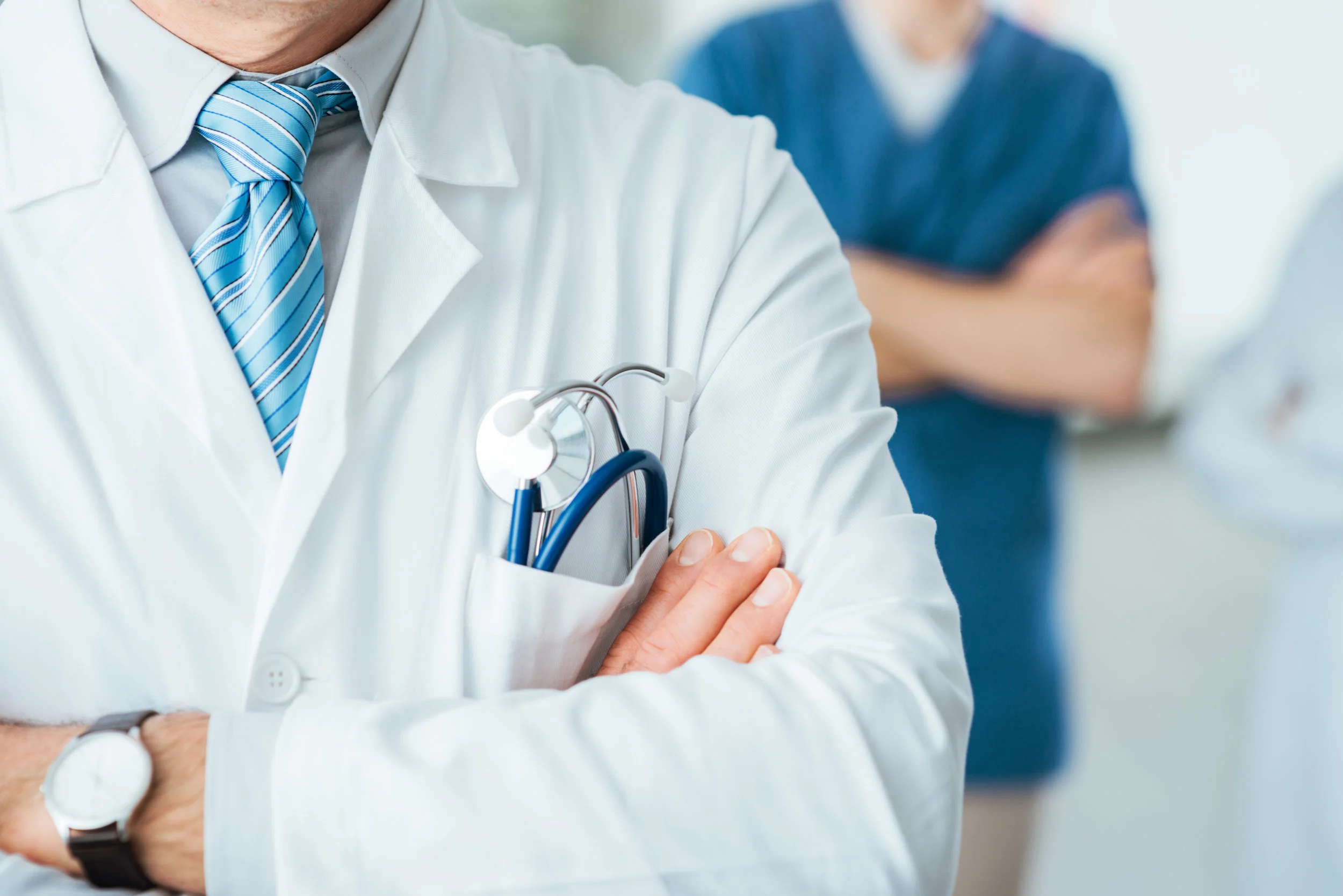 Close up of a professional medical team, including a family practice doctor, standing with arms folded
