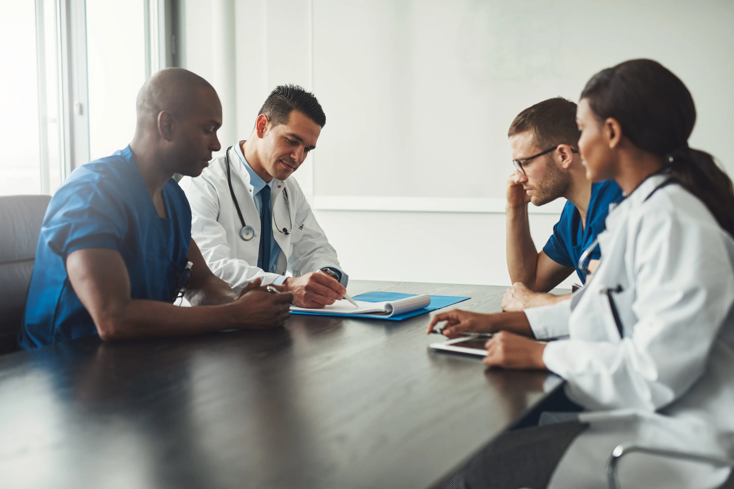Four primary care doctors completing paperwork and evaluating patient history