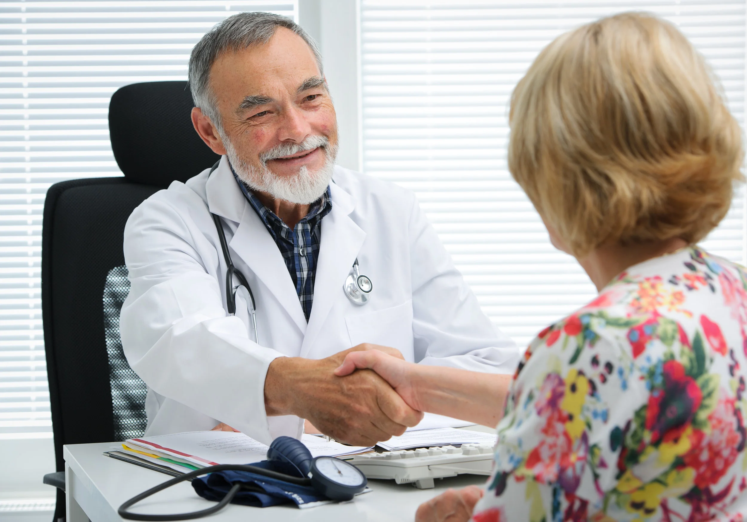 Friendly male family doctor greeting female patient at an annual appointment with a handshake