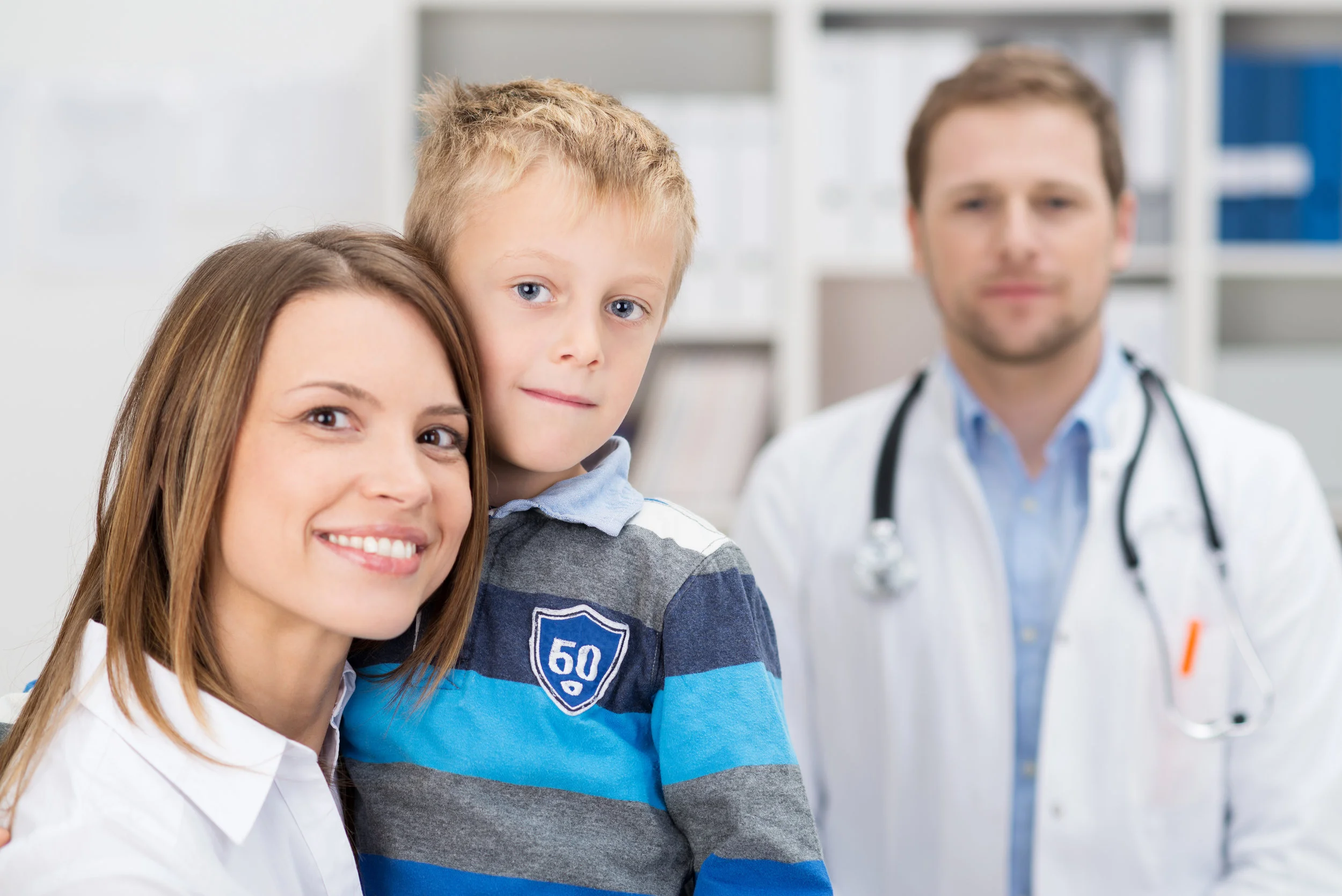Mother holding son with a primary care physician in the background